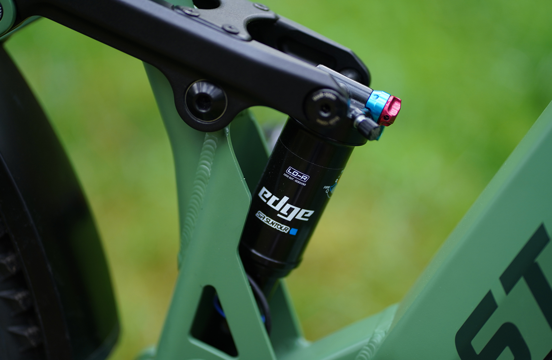 Nahaufnahme eines Stoßdämpfers an einem grünen Fahrrad. Die Marke EDGE und das Modell sind sichtbar.