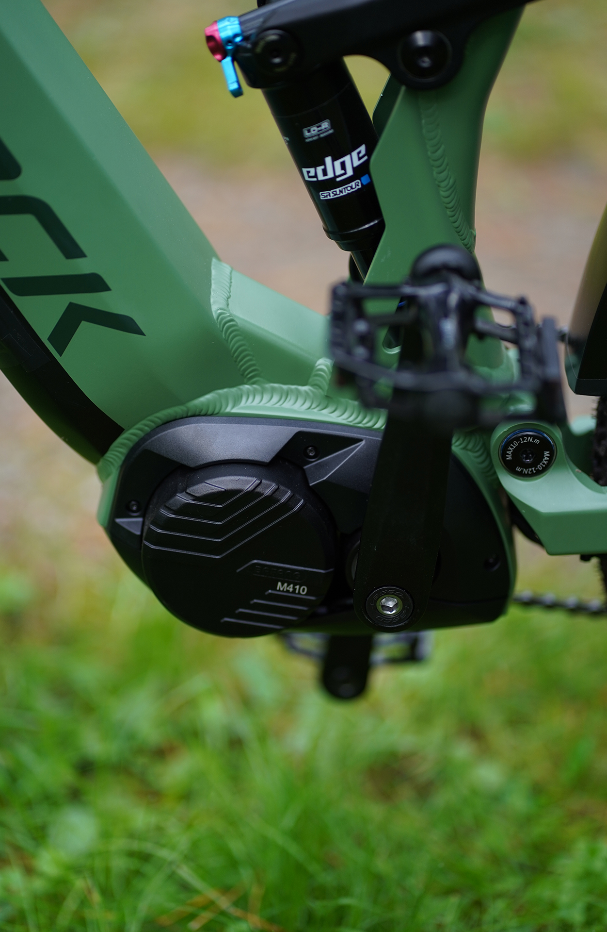 Grünes E-Bike-Detail: Motor, Federung, Pedale. Fokus auf mechanische Teile.