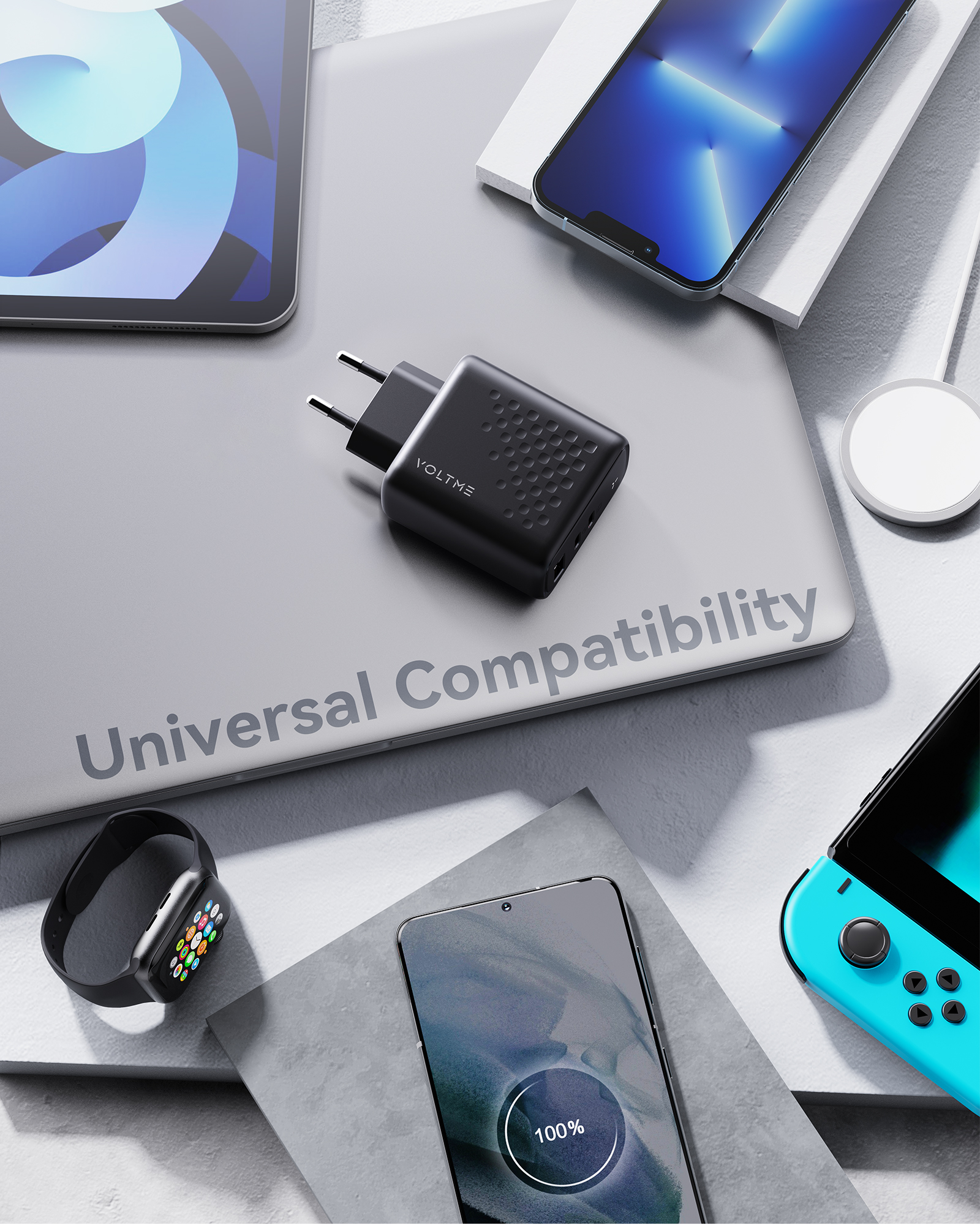 Cargador con accesorios en una superficie, incluyendo teléfono, tableta y reloj inteligente.