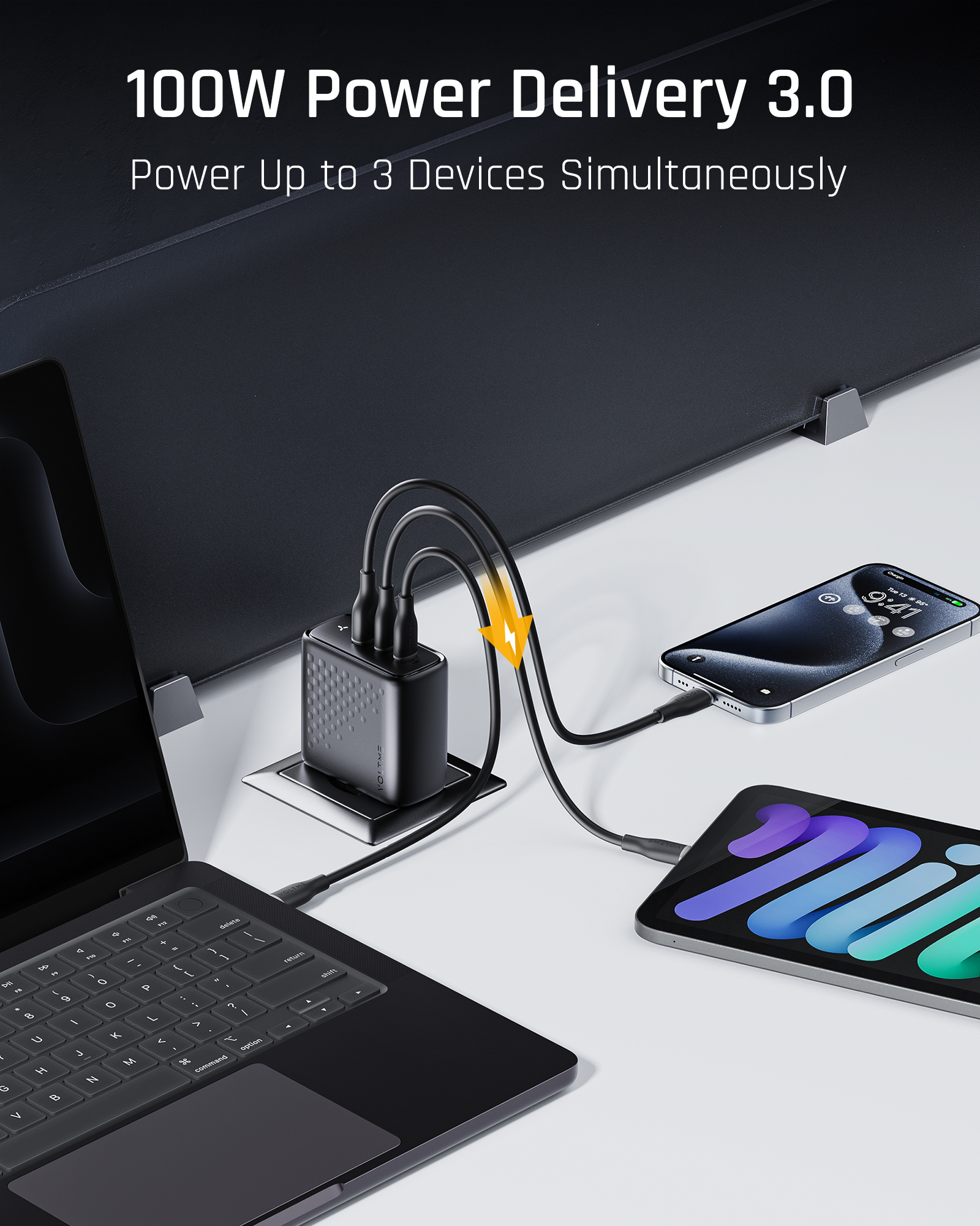 Adaptador de corriente negro con tres cables USB-C cargando un portátil, un teléfono y una tableta.