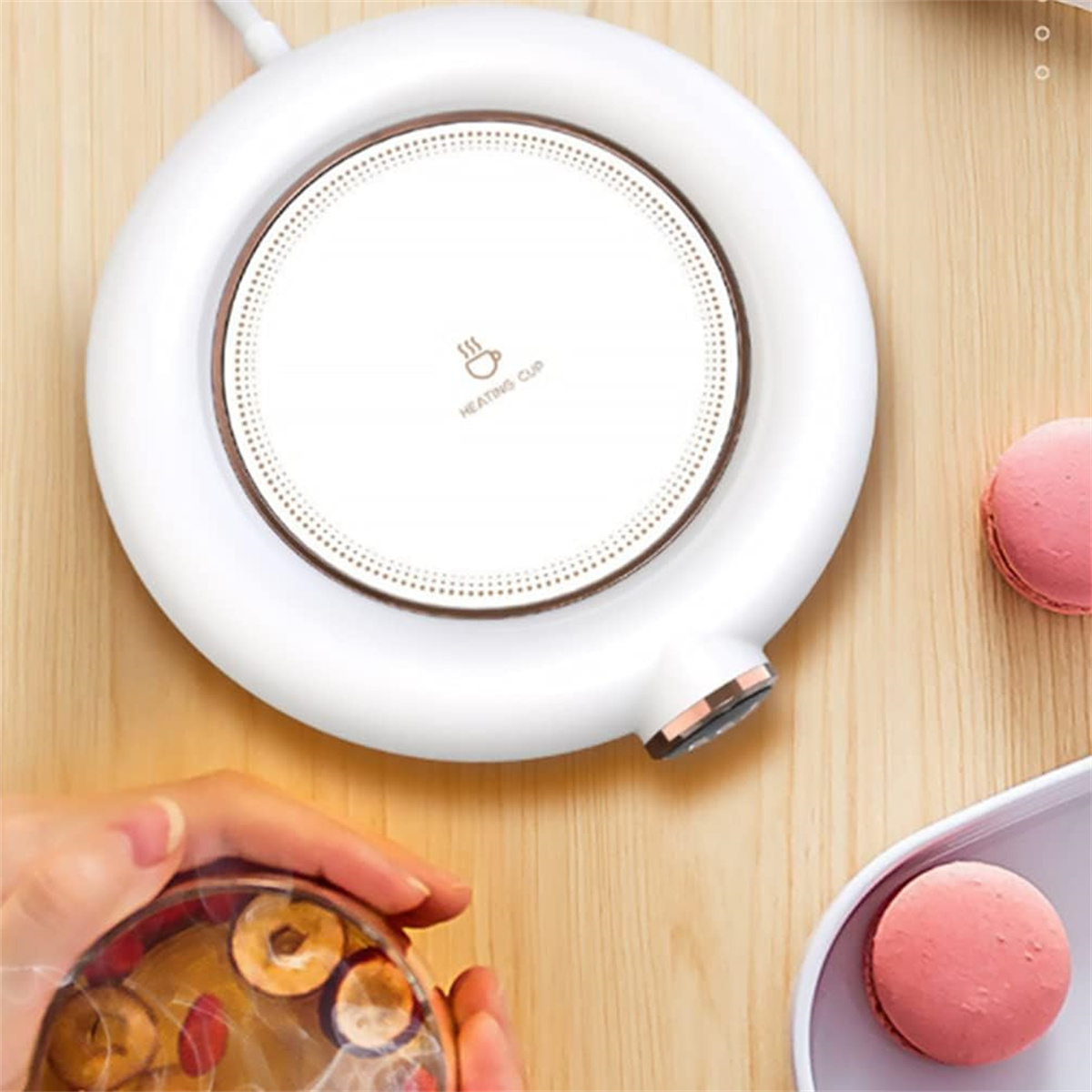 Ein weißer Heizbecherwärmer mit einem rosa Macaron.