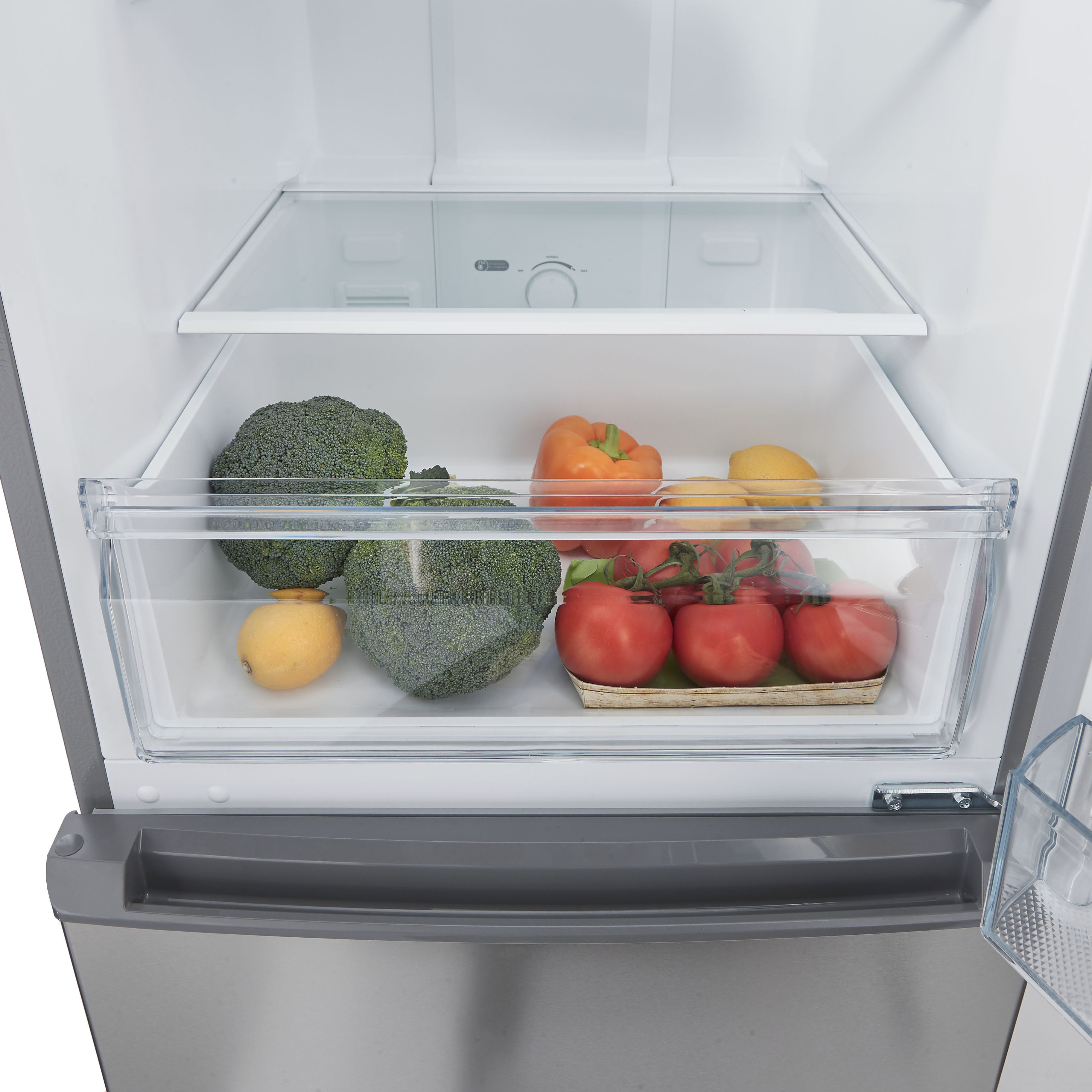 Inside a refrigerator: broccoli, tomatoes, peppers, and lemons are in a clear container. White background.