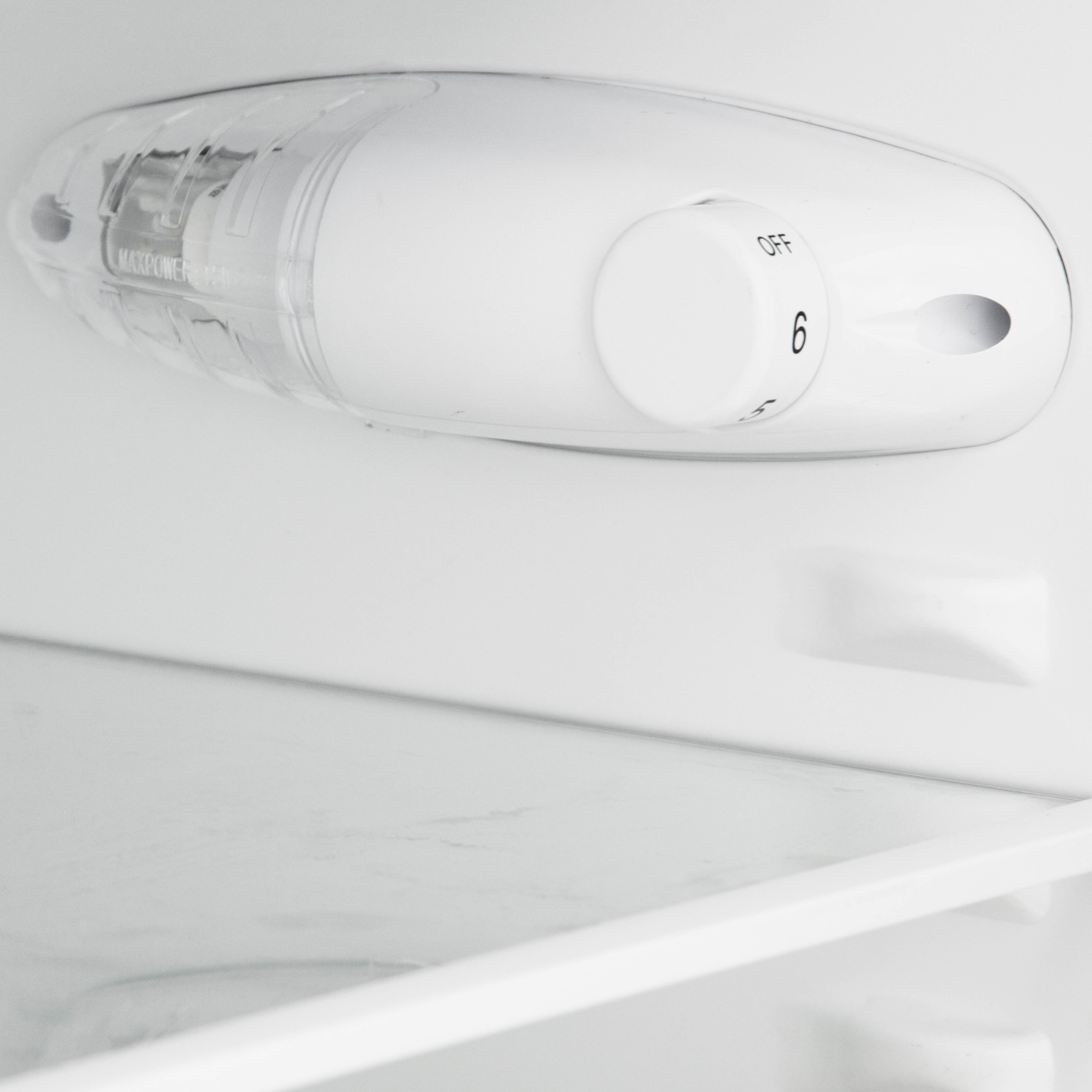 Een wit koelkastinterieur met een bedieningspaneel en een klein, helder, wit licht.