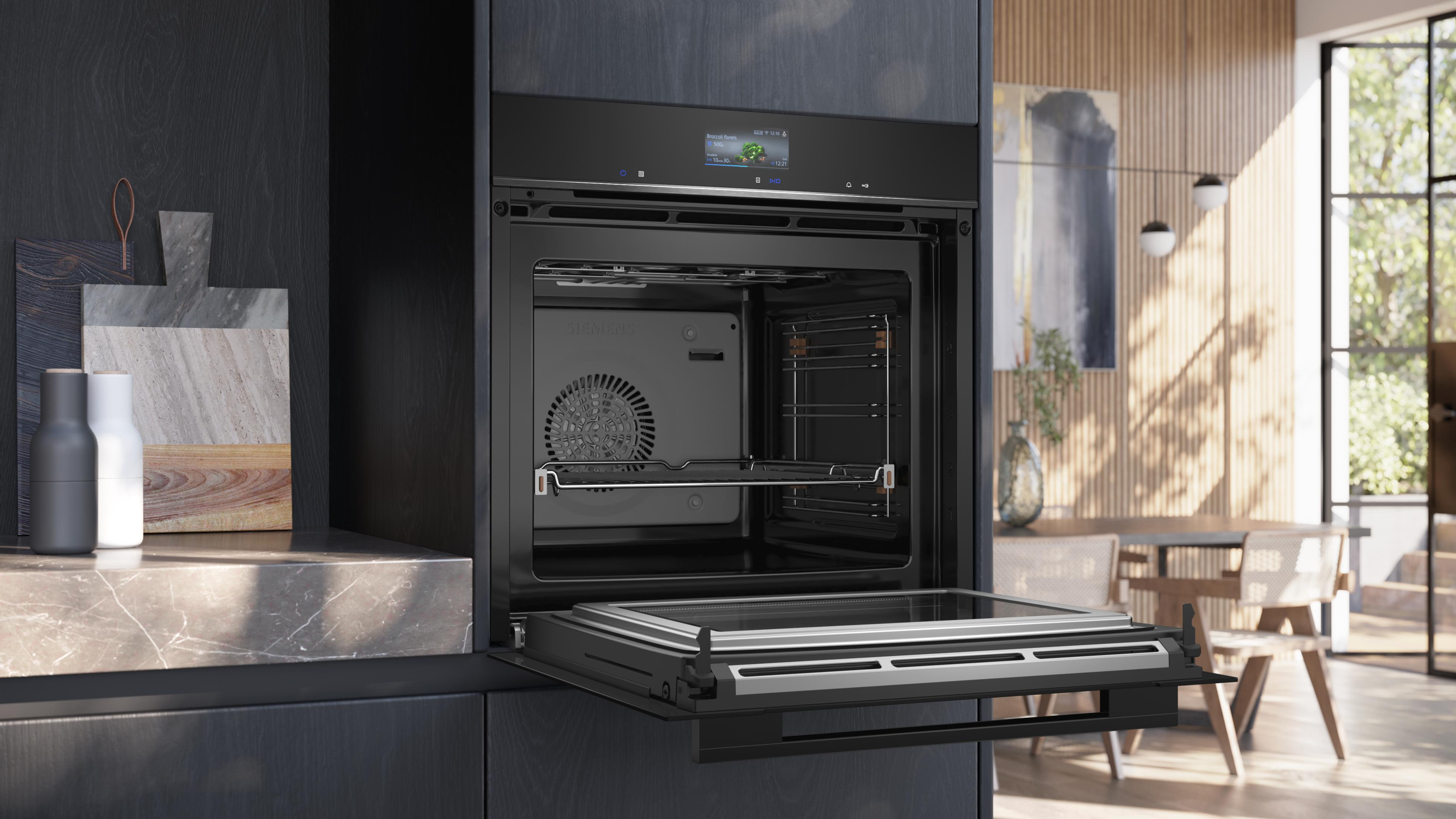 Horno negro moderno con puerta abierta, interior visible. En una cocina oscura.