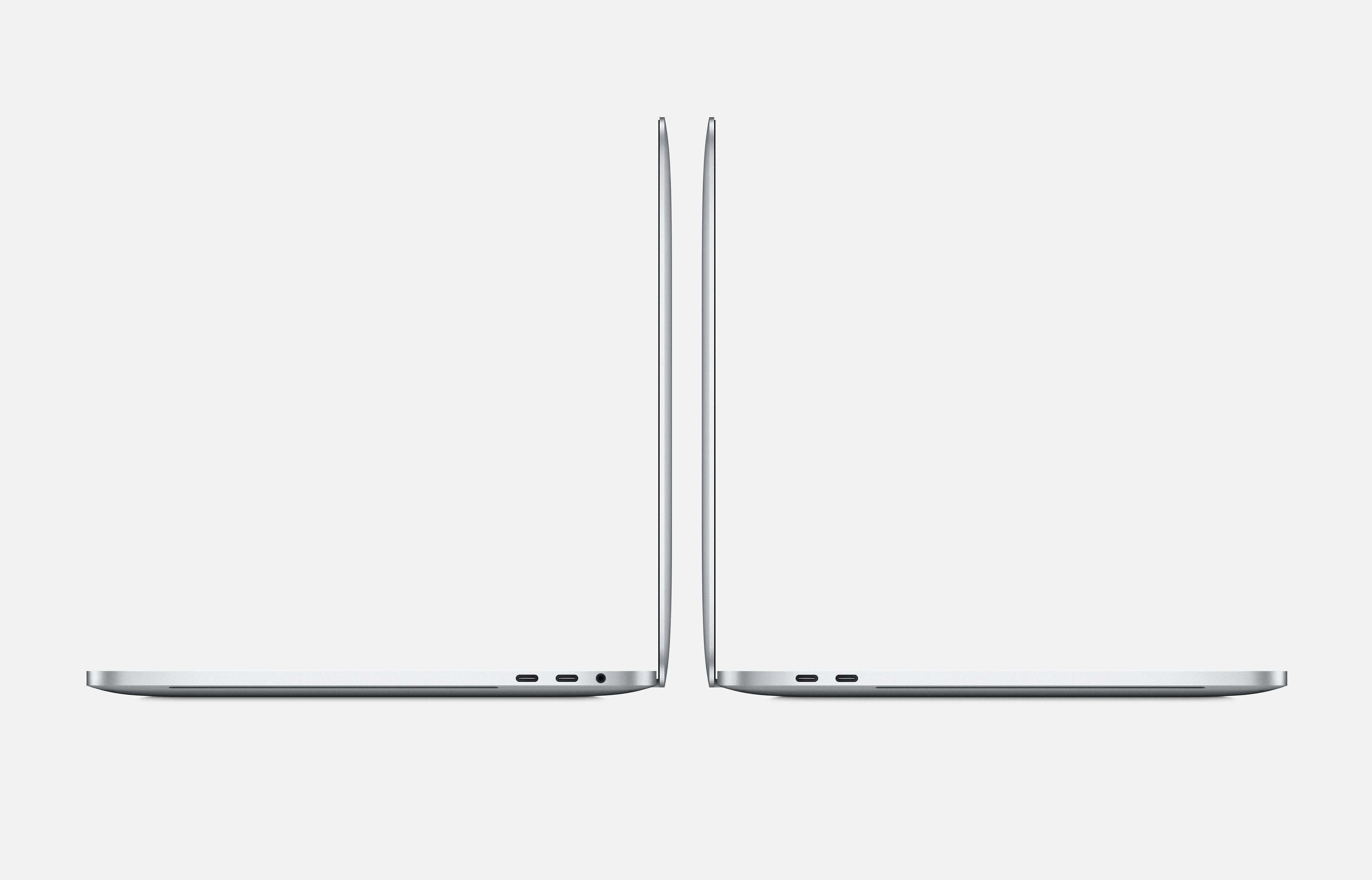 Dos laptops plateados uno al lado del otro, mostrando una vista de perfil sobre fondo blanco.