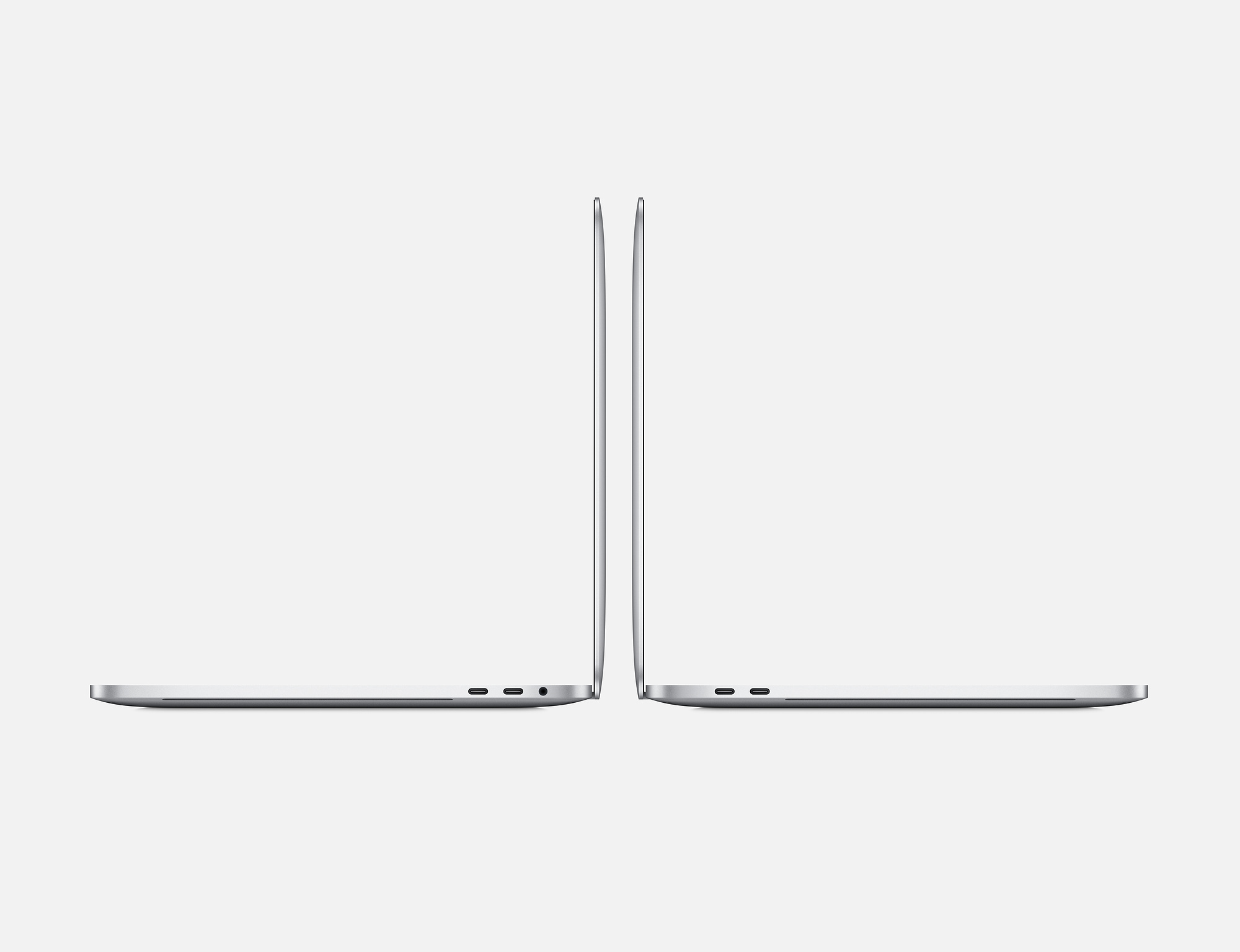 Dwa srebrne laptopy, widok z boku, na białym tle.