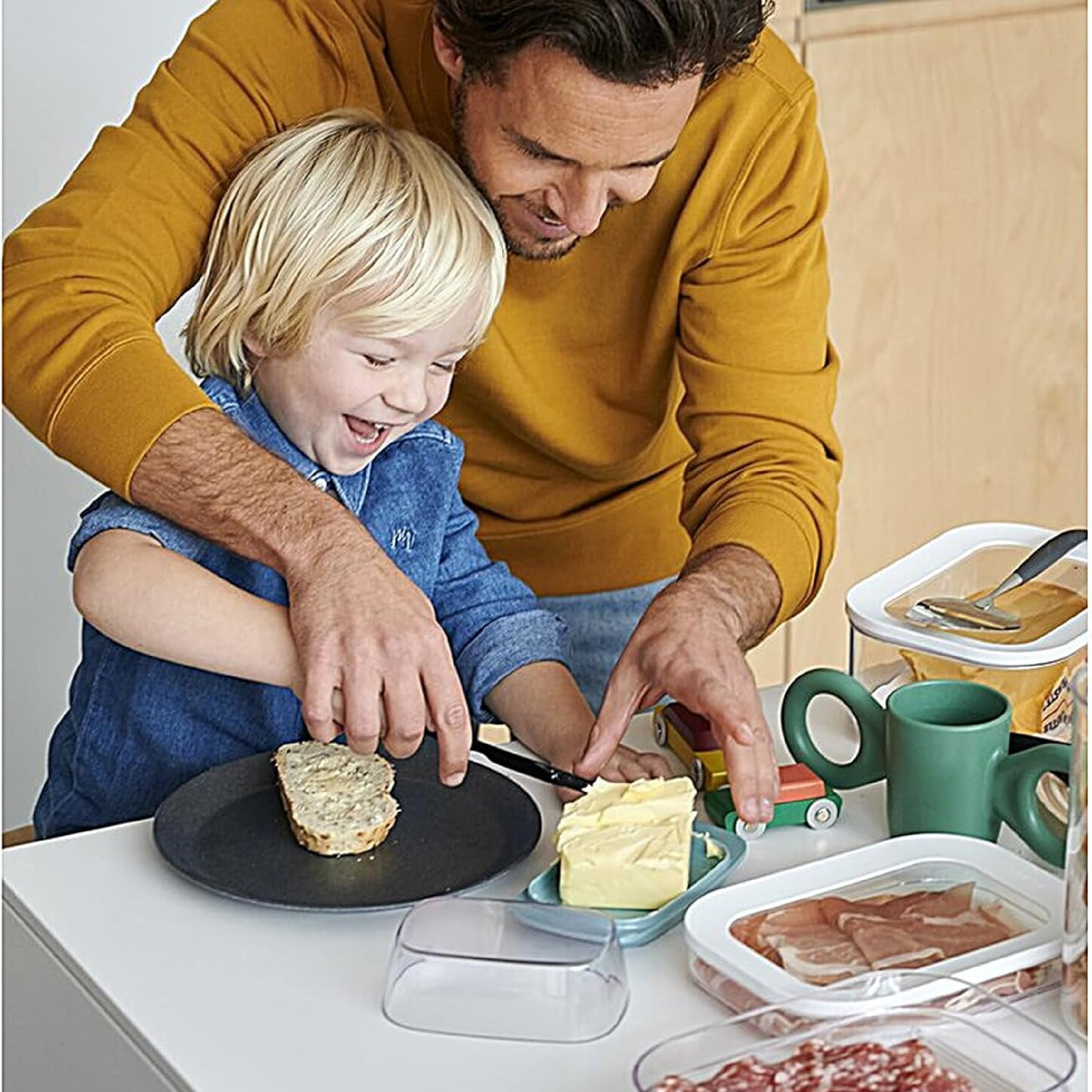 Ein Mann und ein Kind bereiten gemeinsam Essen zu. Sie lächeln und sind glücklich.