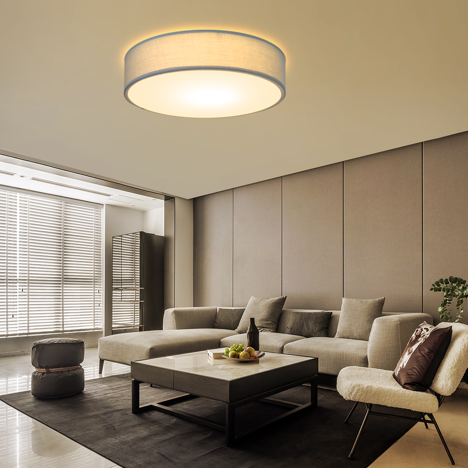 Nowoczesny salon z okrągłą lampą sufitową, sofą, stolikiem kawowym i fotelem.