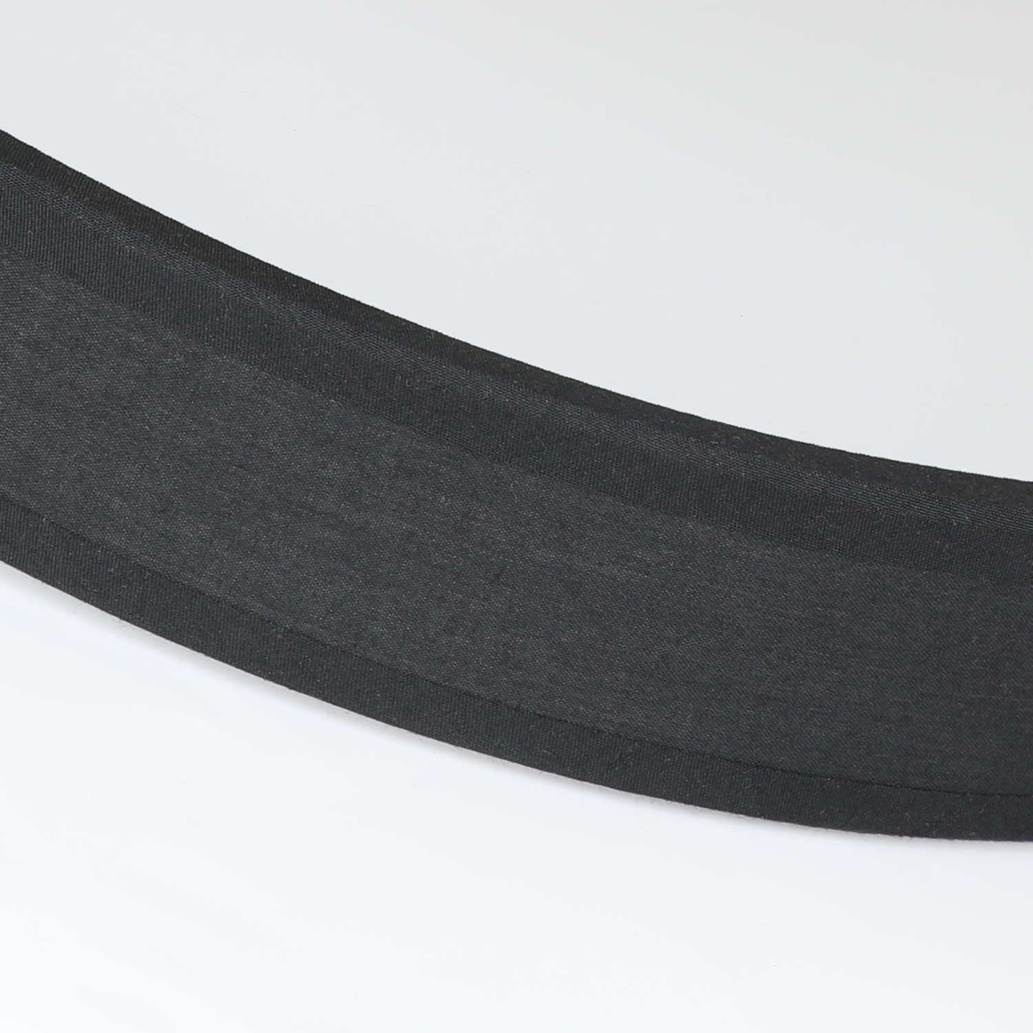 Czarny materiał, być może pasek, na białym tle. Materiał ma fakturę.