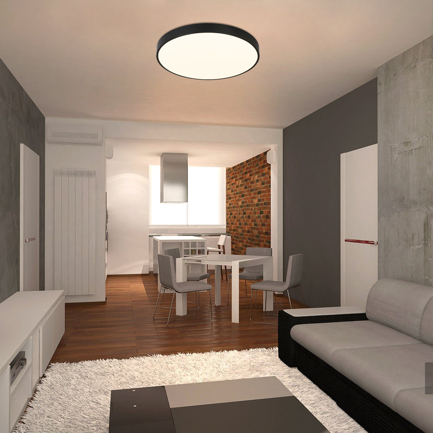 Wnętrze salonu z białymi ścianami, drewnianą podłogą i dużą okrągłą lampą sufitową.