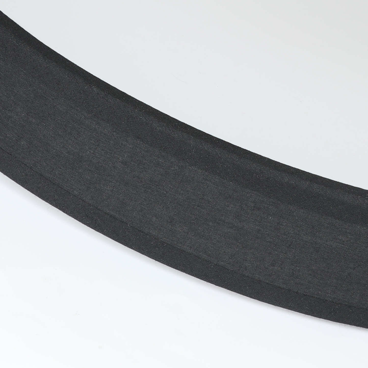 Zbliżenie czarnego, teksturowanego materiału na białym tle. Zakrzywiony kształt.