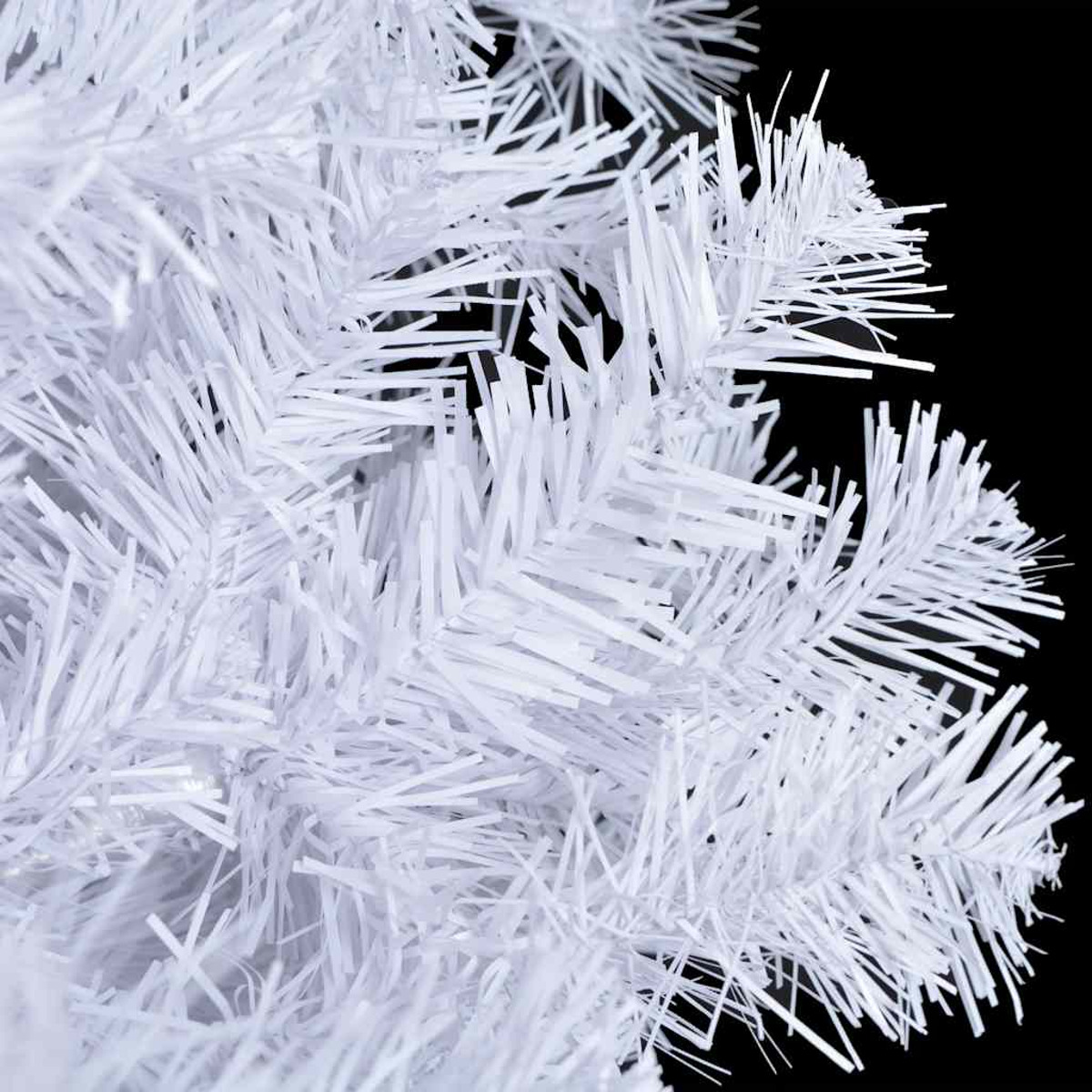 Nahaufnahme von einem weißen künstlichen Weihnachtsbaumzweig vor schwarzem Hintergrund.