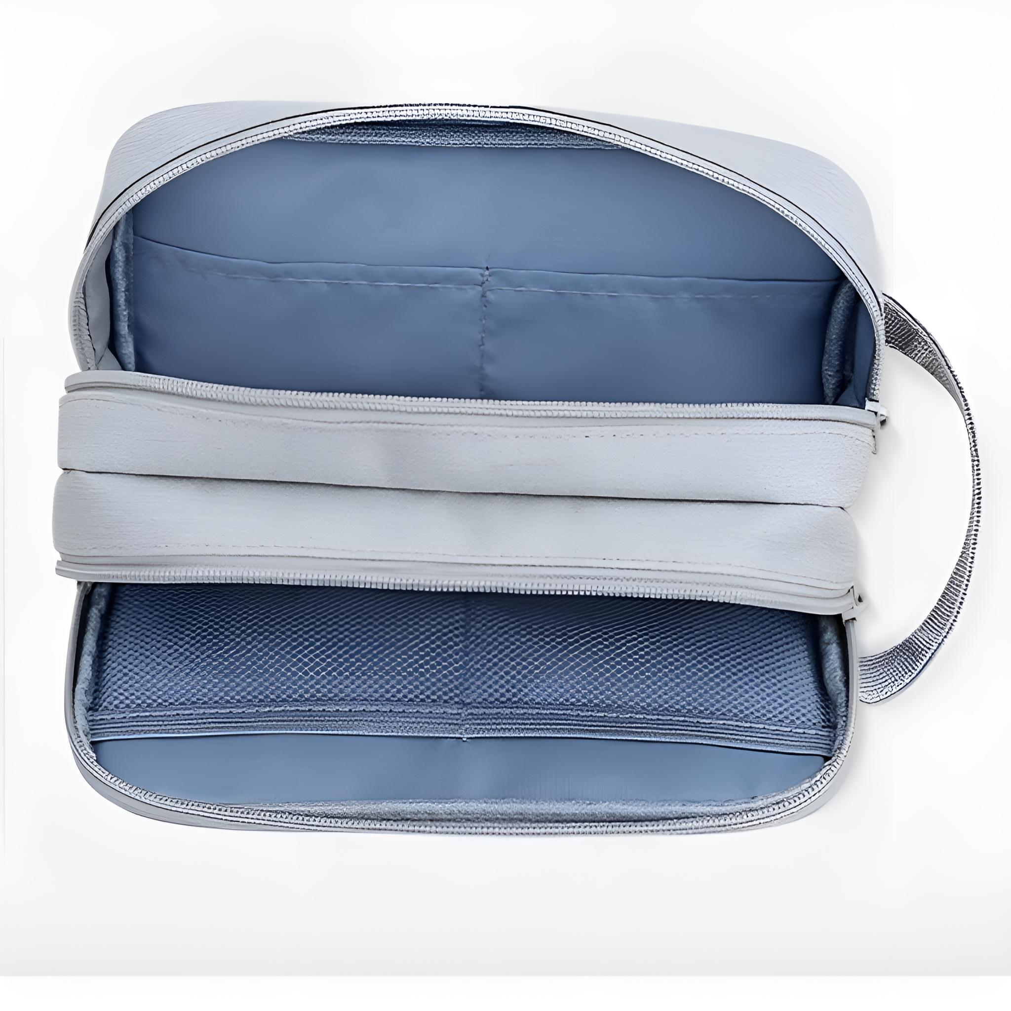 Graue, offene Reisetasche. Innen sind blaue Fächer und eine Netztasche sichtbar.