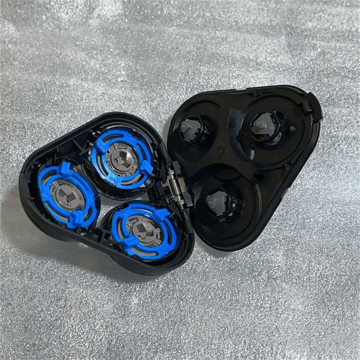 Geöffneter Rasierkopf mit drei blauen und silbernen Klingen.