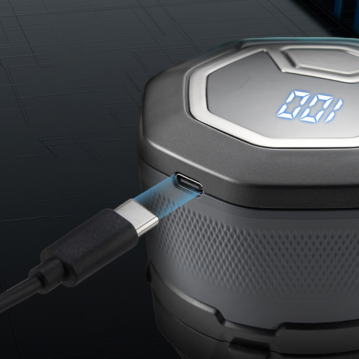 Ein schwarzes Gerät mit einem USB-C-Anschluss, das von einem schwarzen Kabel aufgeladen wird. Der Bildschirm zeigt Zahlen an.