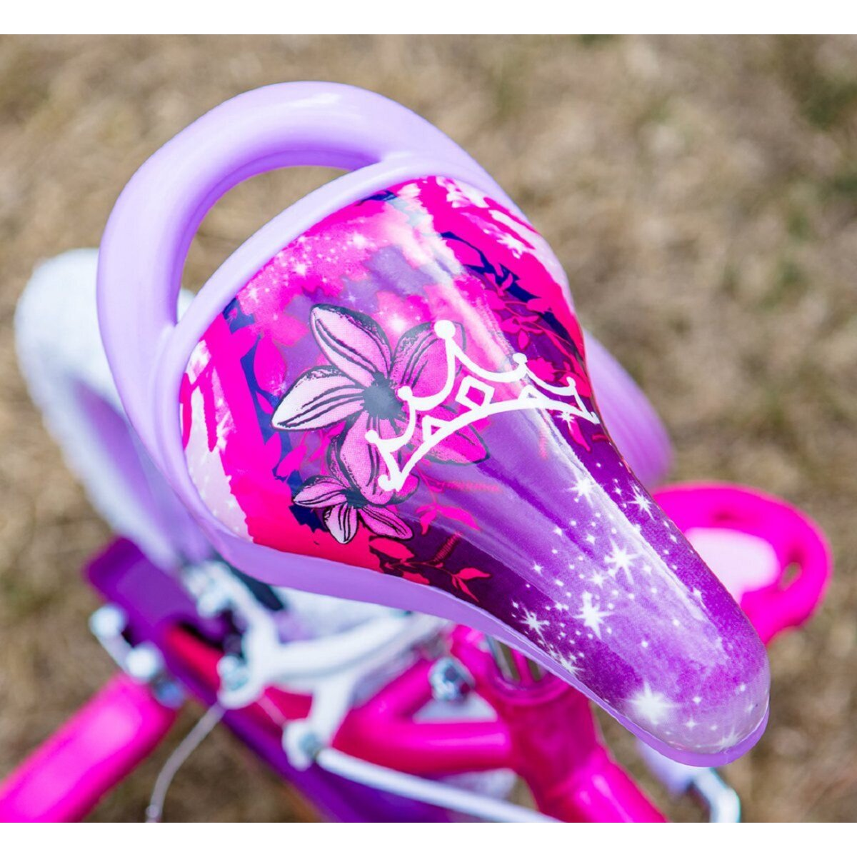 Ein pinker Fahrradsattel mit floralem Design und Krone. Der Sattel ist an einem pinken Fahrrad.