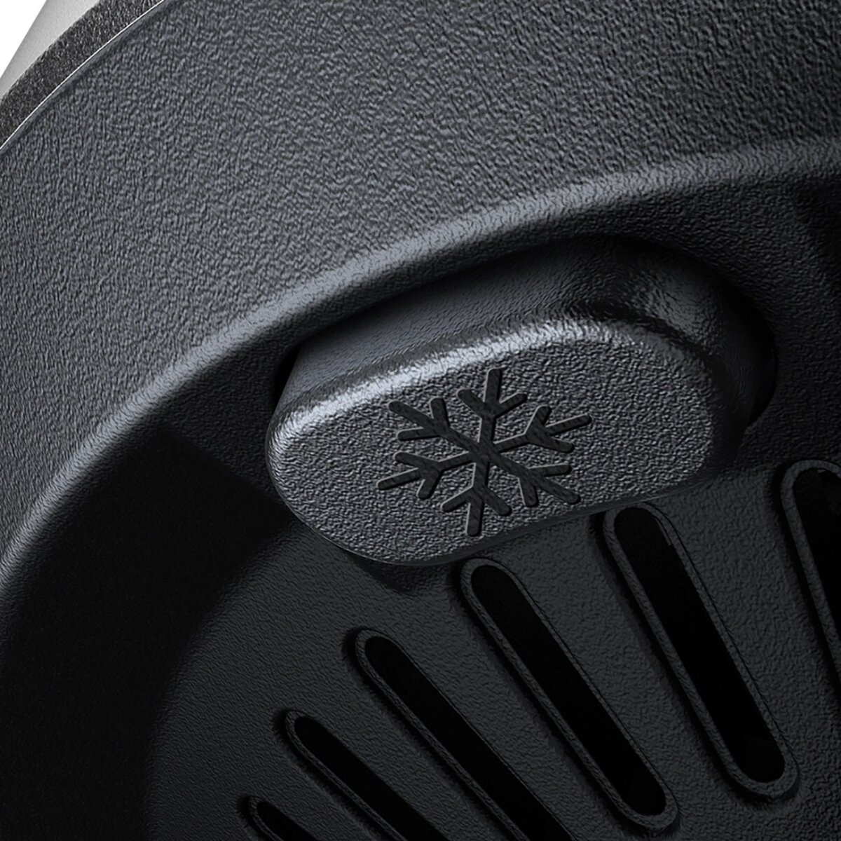 Zbliżenie czarnego przycisku urządzenia z symbolem płatka śniegu. Jest to element sterowania.