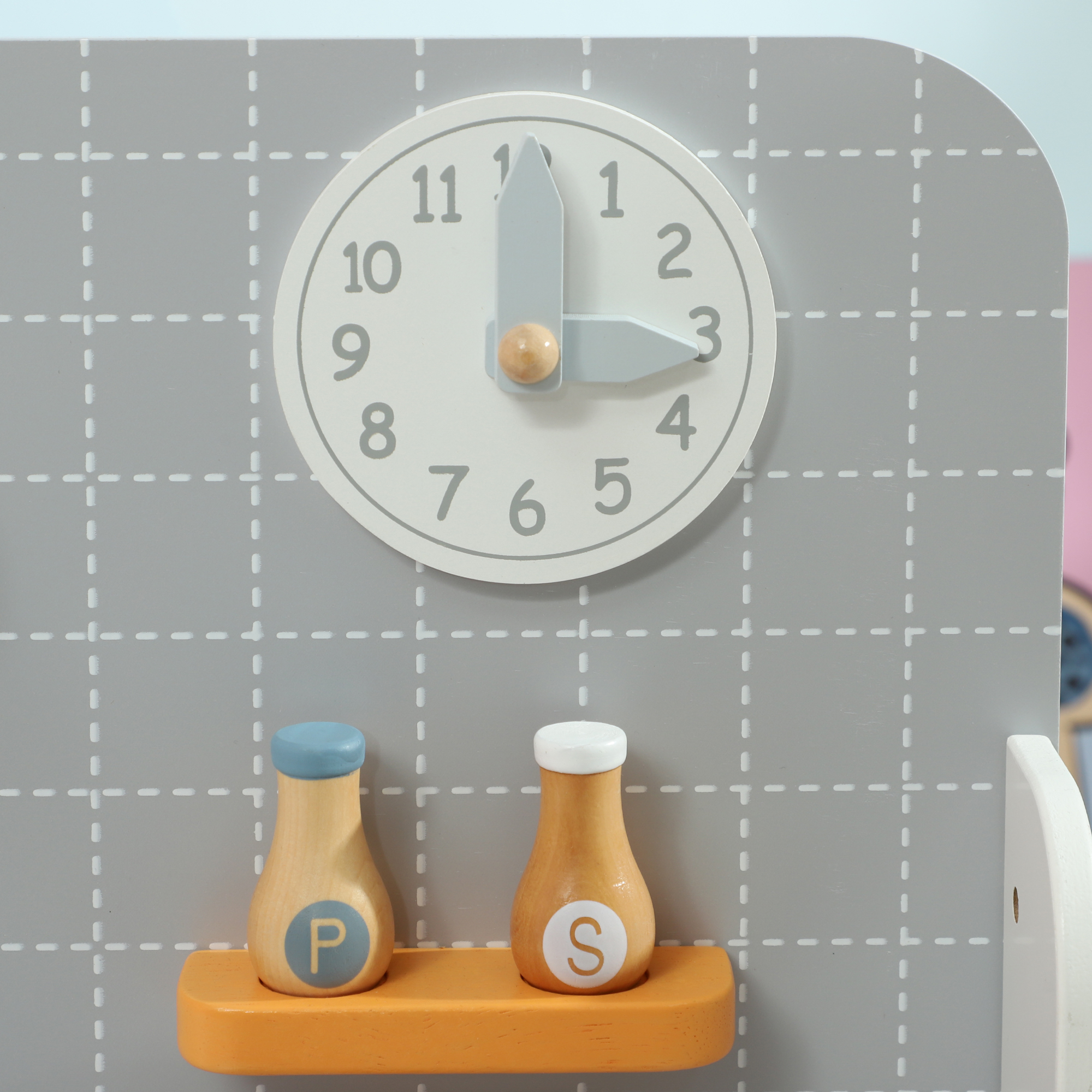 Un reloj de cocina de juguete muestra las 3 en punto, con saleros y pimenteros debajo.