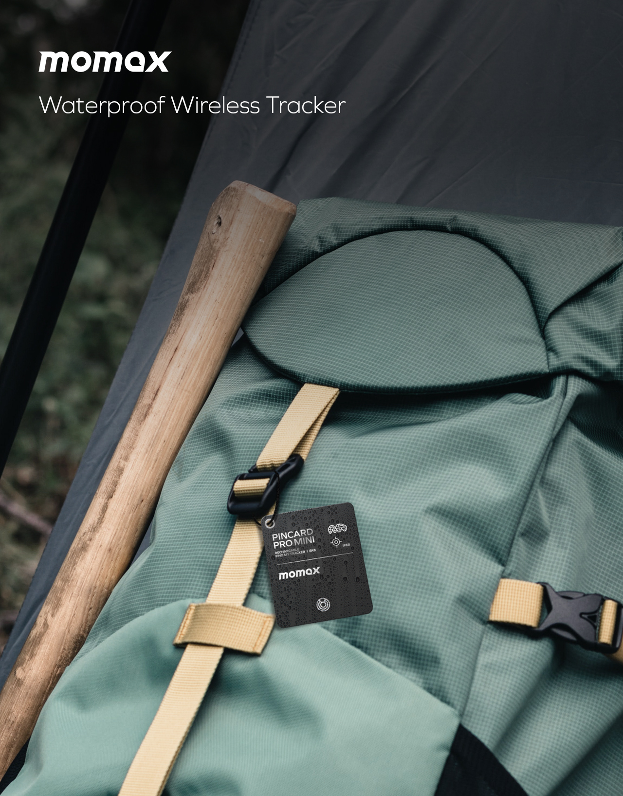 A backpack with a wooden stick and a Momax wireless tracker. The tracker is black. The backpack is green.