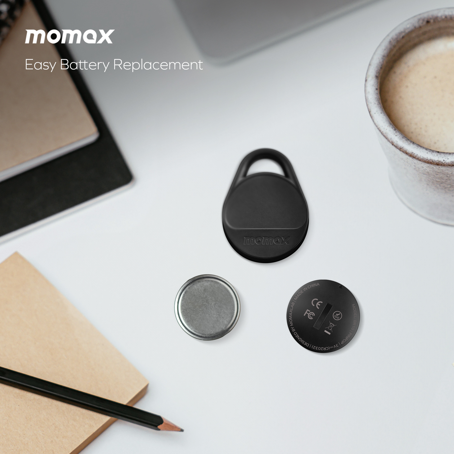Black tracker, battery and battery cover on white surface. Text 'momax'.