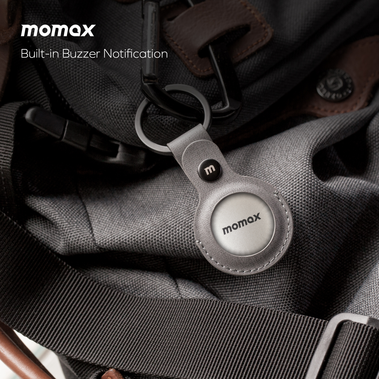 Momax AirTag holder with a gray leather case and a metal ring, on a bag.