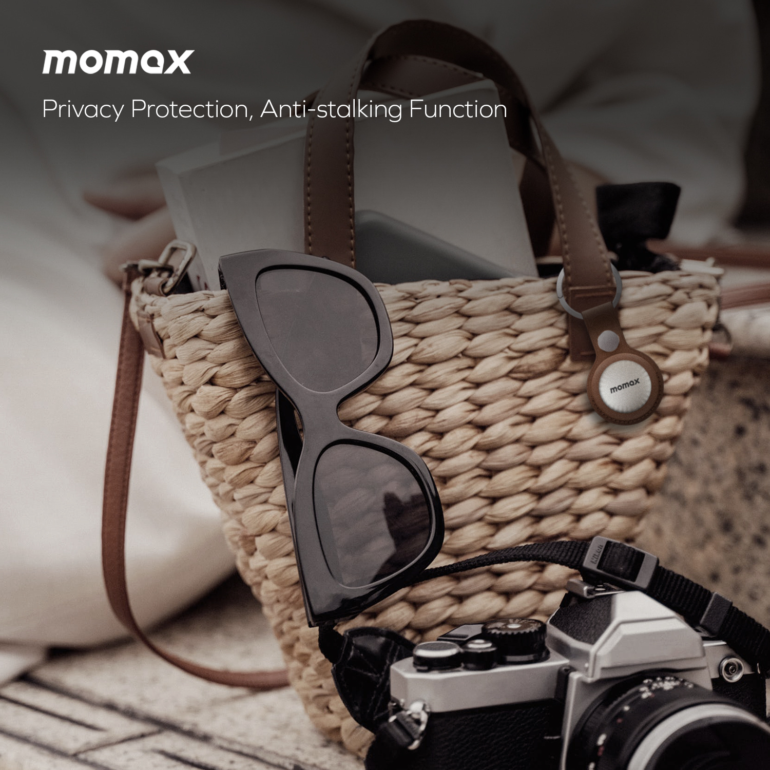 Momax tracker on bag with sunglasses. Black sunglasses and Momax tracker are visible.