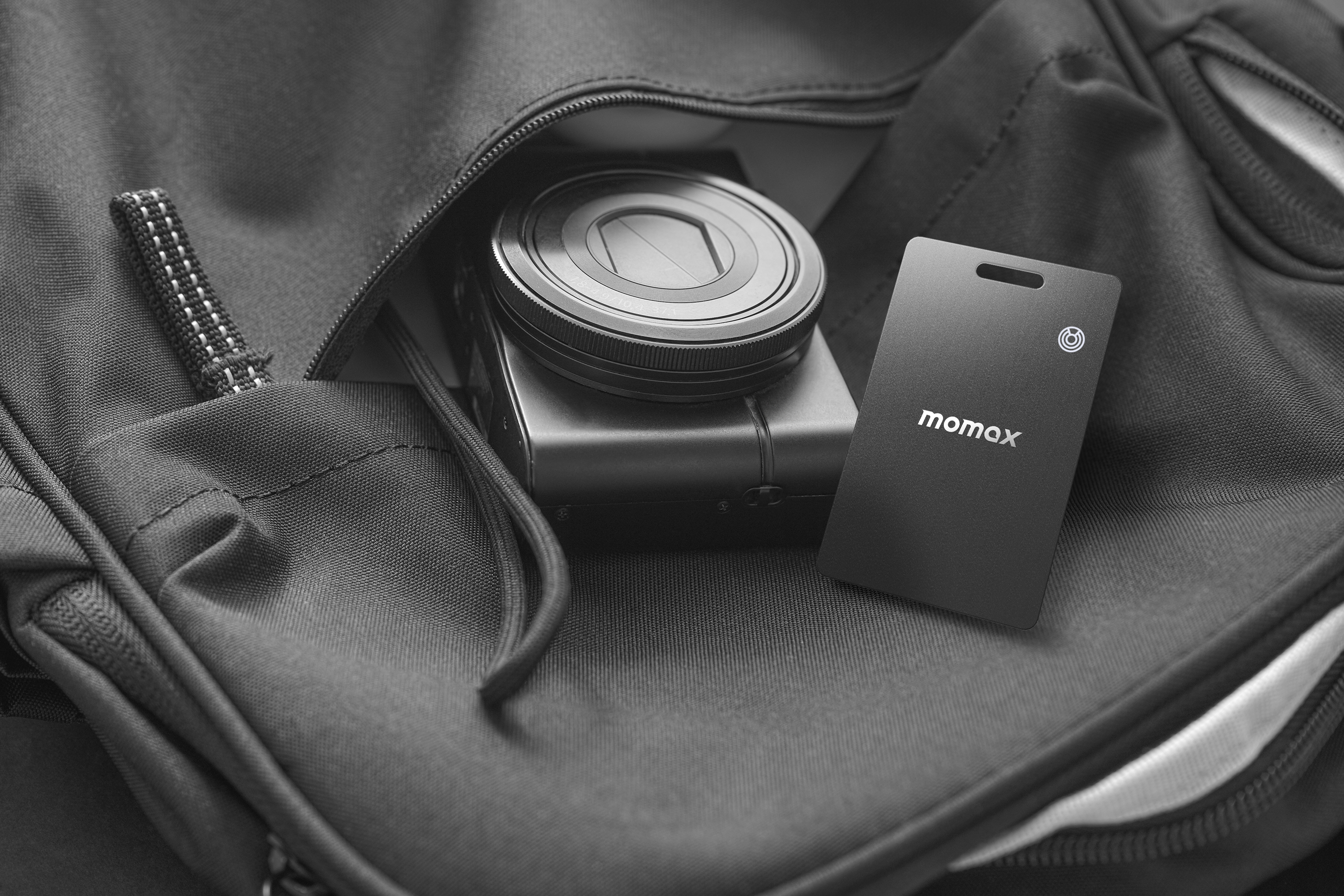 A black bag with a camera and a momax tracker inside.