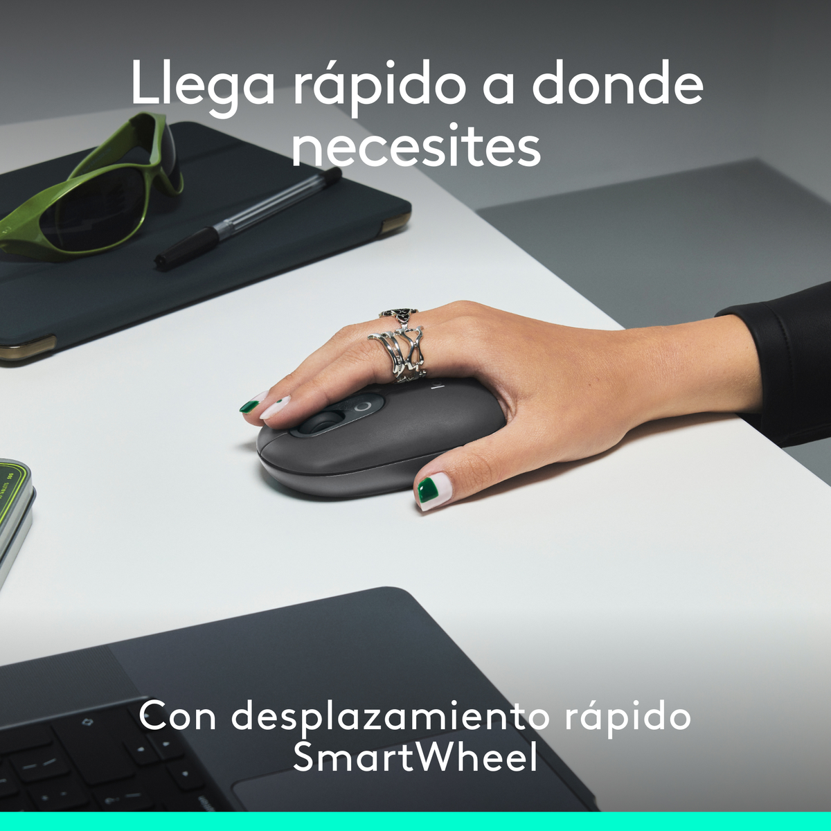 Dłonie osoby używającej klawiatury i myszy na biurku z akcesoriami i komputerem.