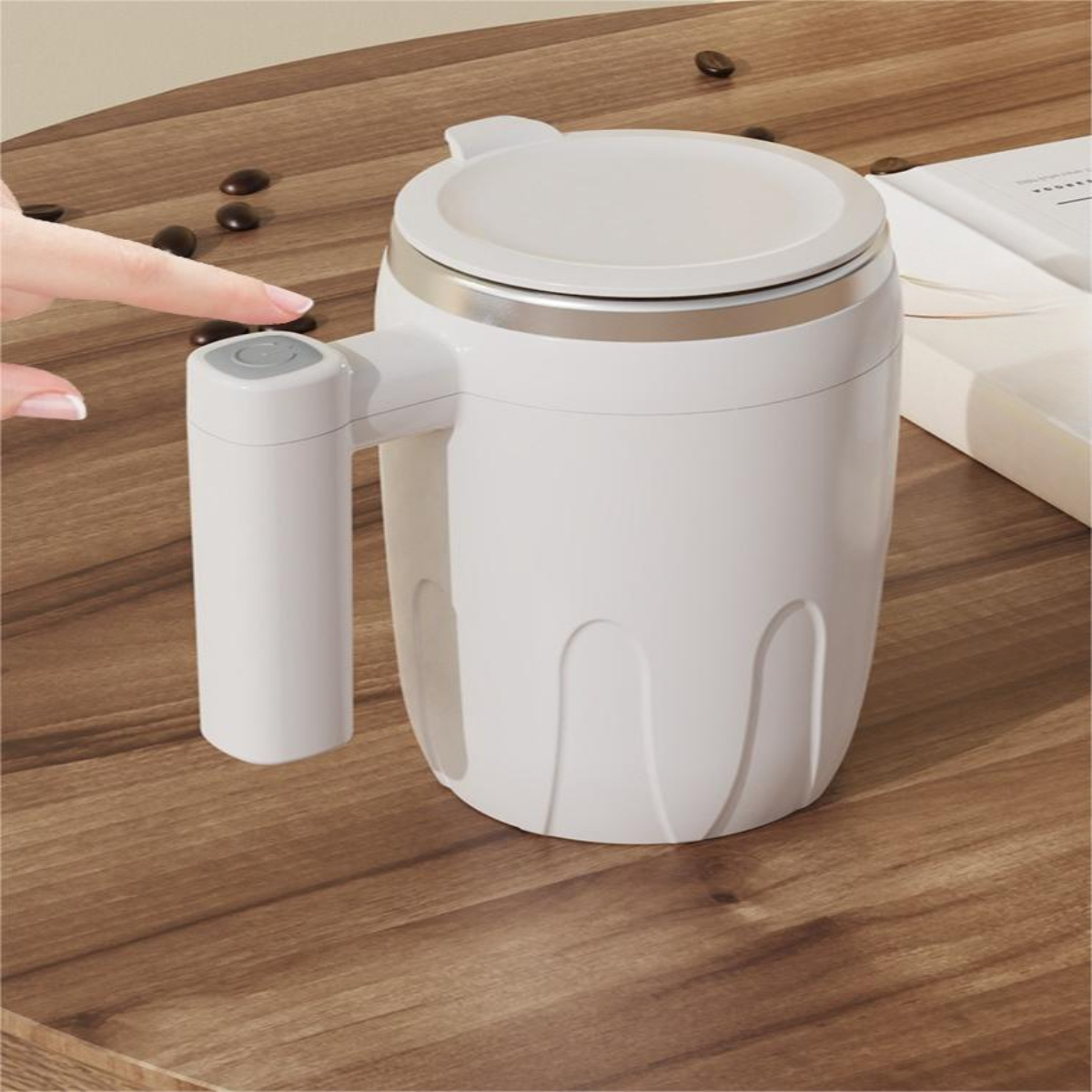 Ein weißer Becher mit Deckel und Griff, der Knopf wird auf einem Holztisch mit einem Finger gedrückt.