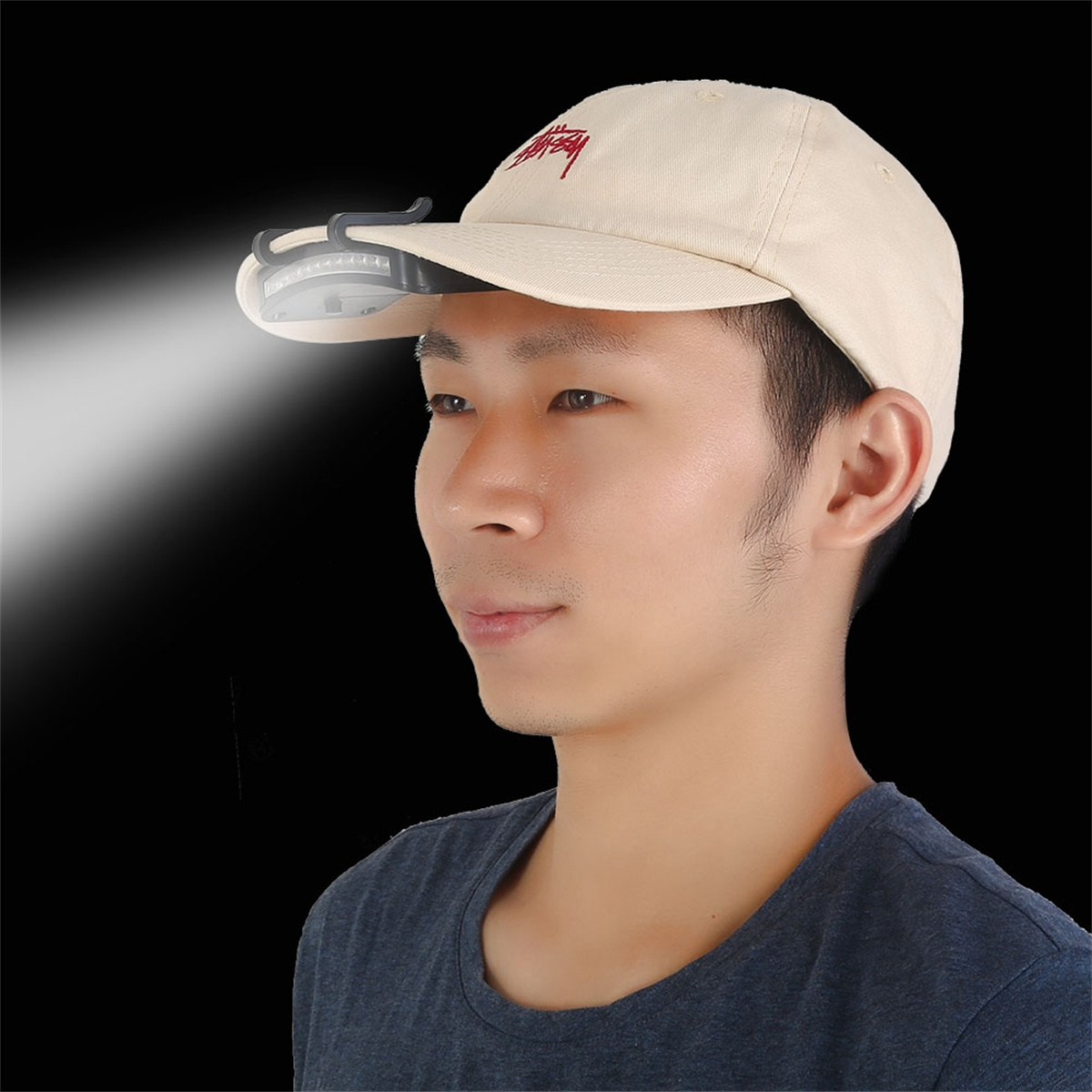 Ein Mann mit einer Kappe mit hellem Licht, das nach vorne scheint. Dunkler Hintergrund.