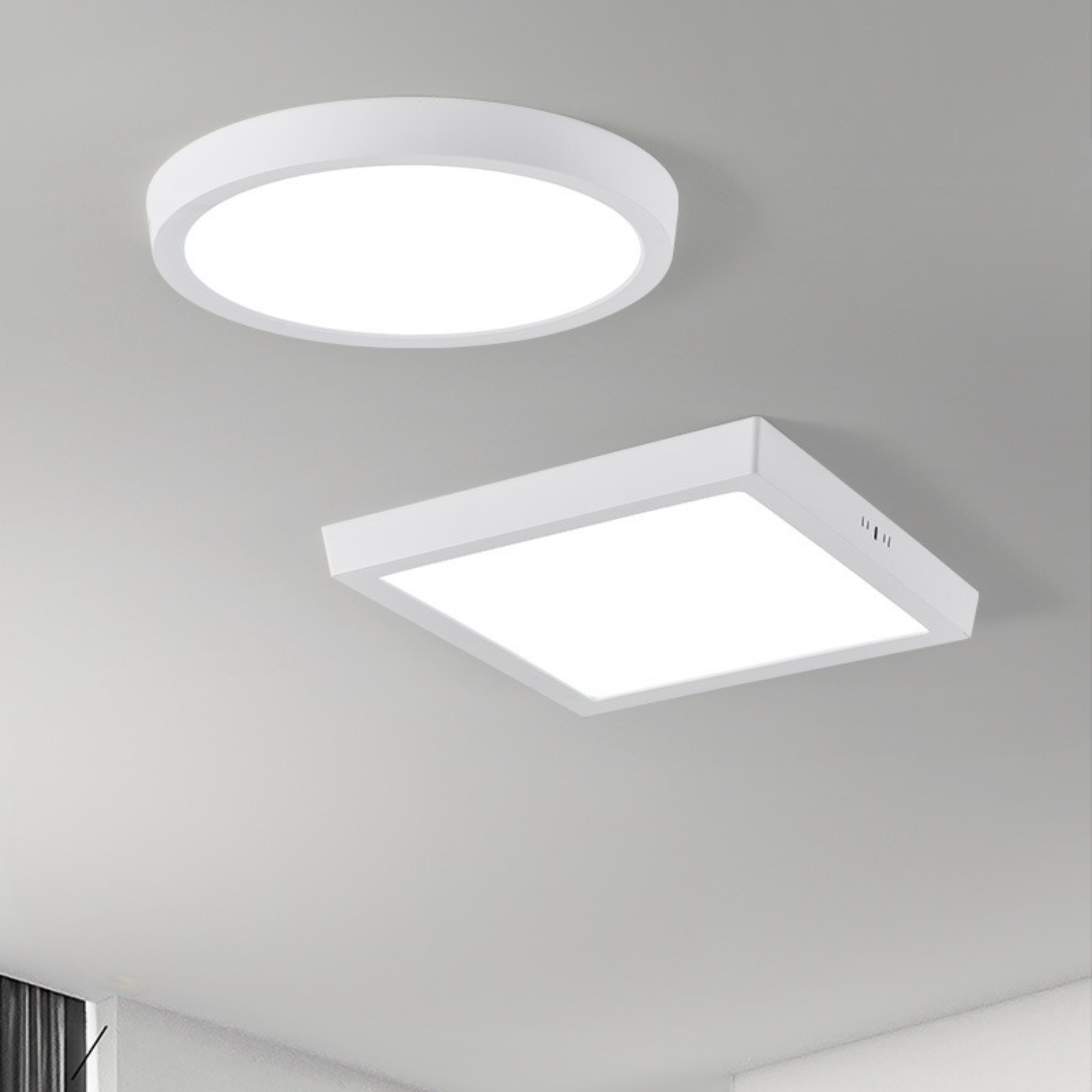 Zwei weiße LED-Deckenleuchten, eine runde und eine quadratische. Beide sind beleuchtet. Die Decke ist grau.