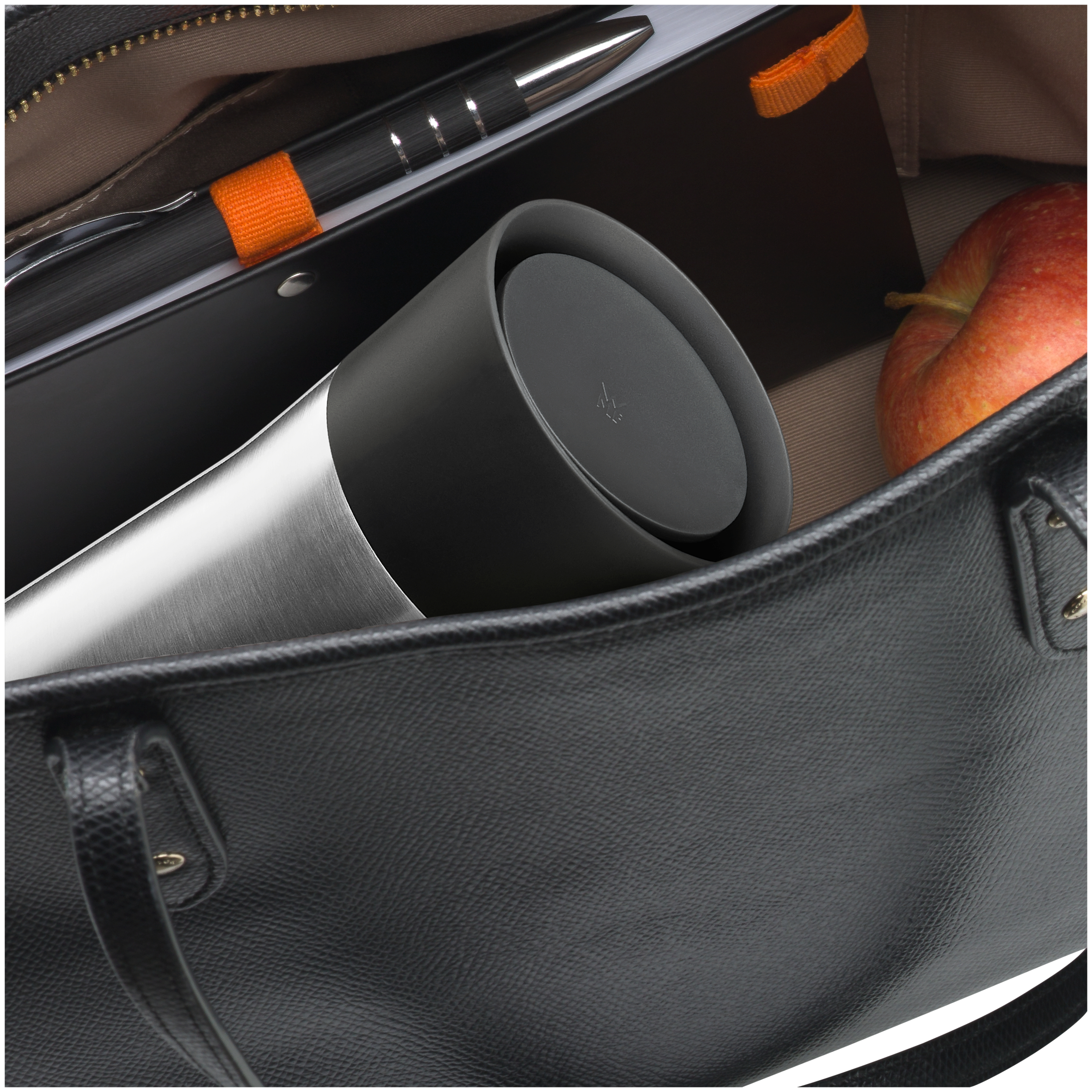 Eine schwarze Ledertasche mit einer silbernen Thermoskanne, Stift, Notizblock und einem Apfel darin.