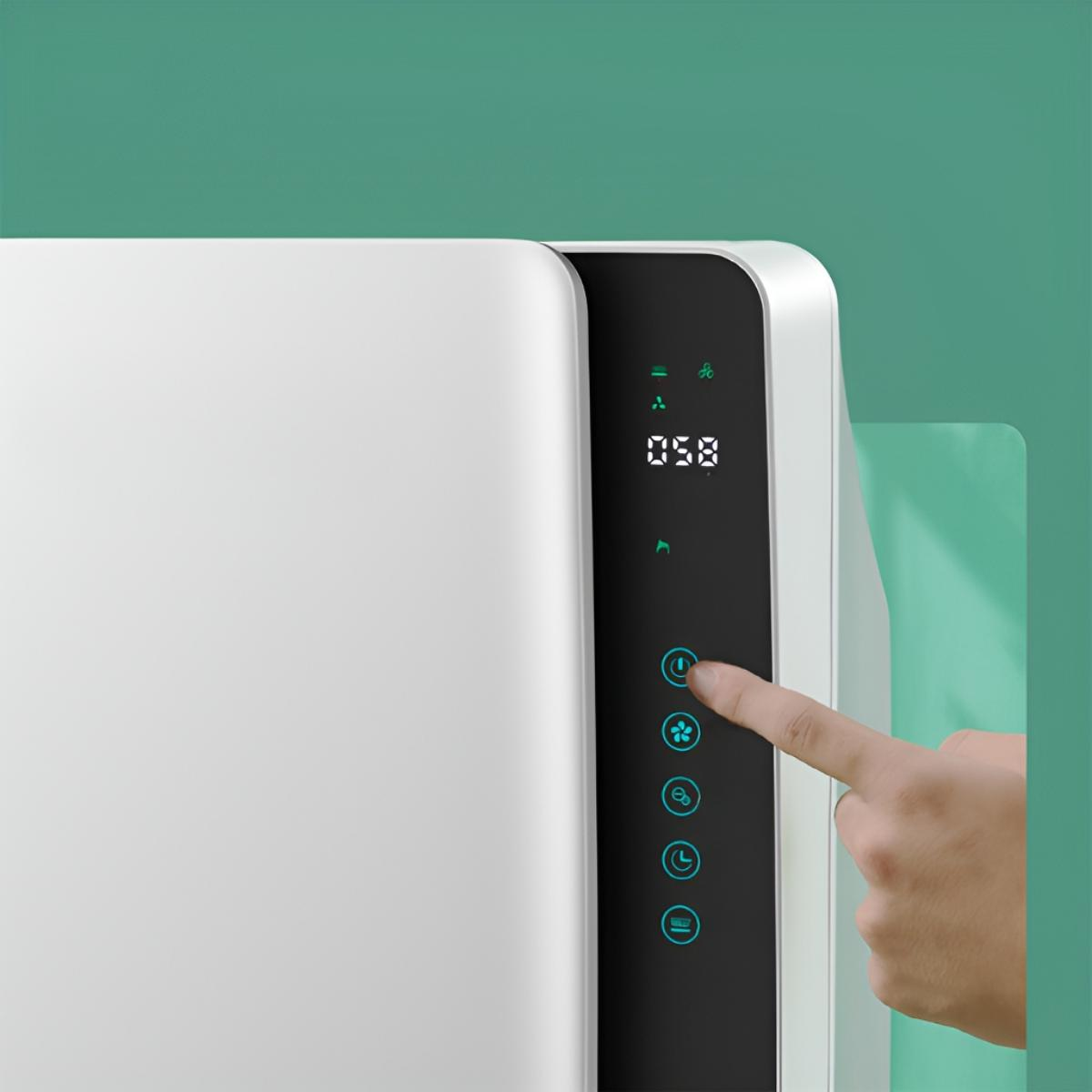 Weißes Gerät mit digitaler Anzeige, ein Finger drückt einen Knopf. Hintergrund: grün und weiß.
