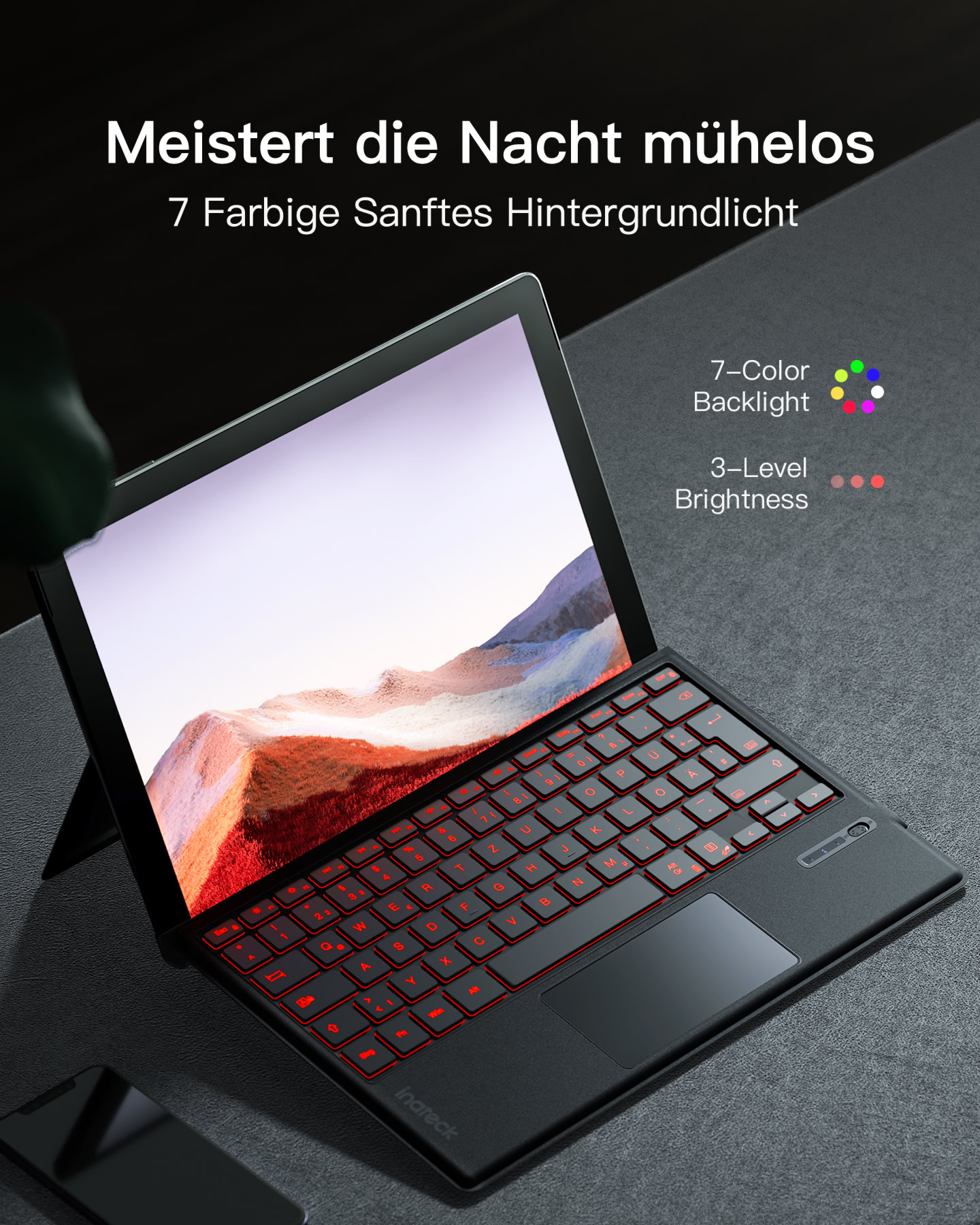 Tastiera di un laptop nero con retroilluminazione rossa, paesaggio sullo schermo.