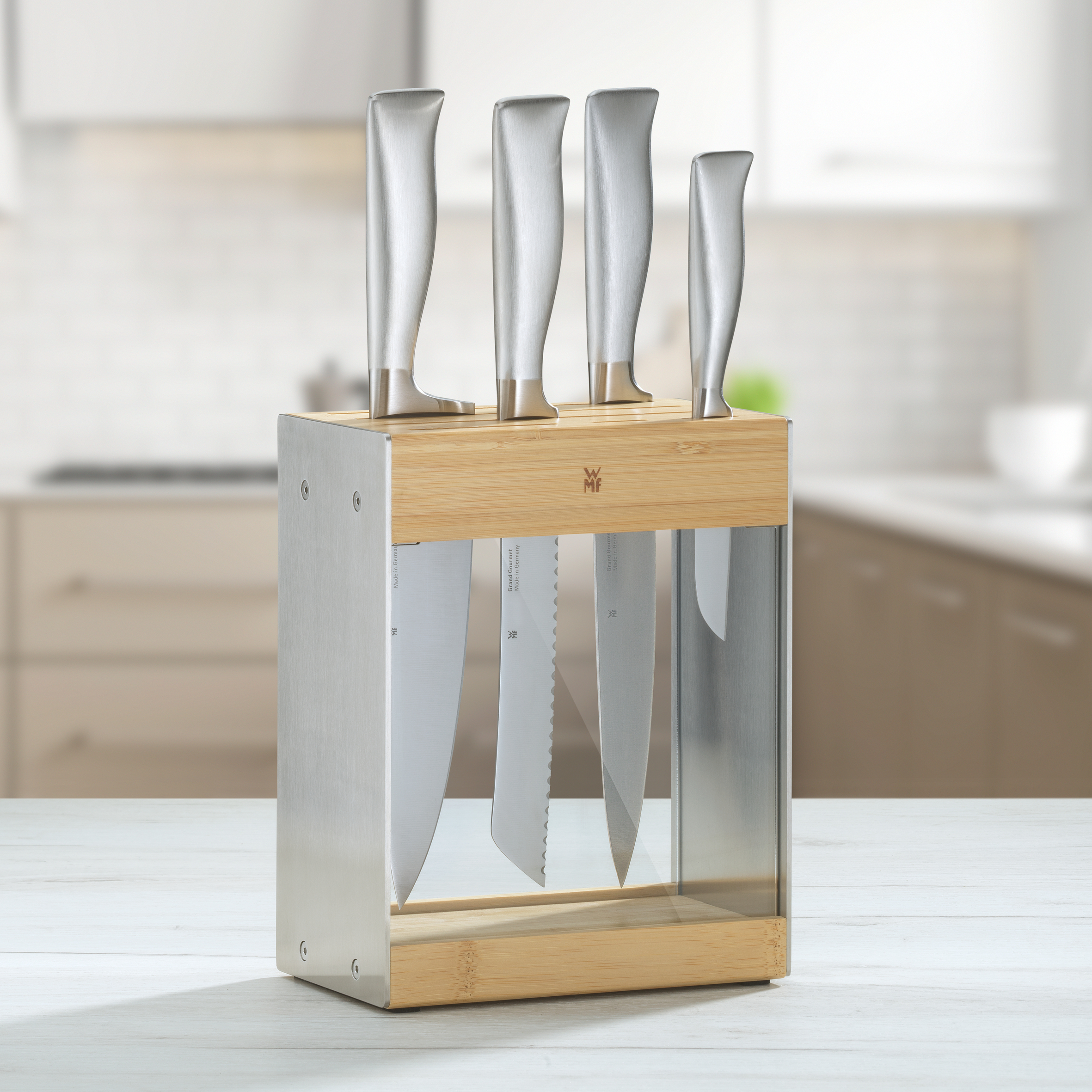 Messerset in Holz- und Glasblock, auf weißem Tisch.