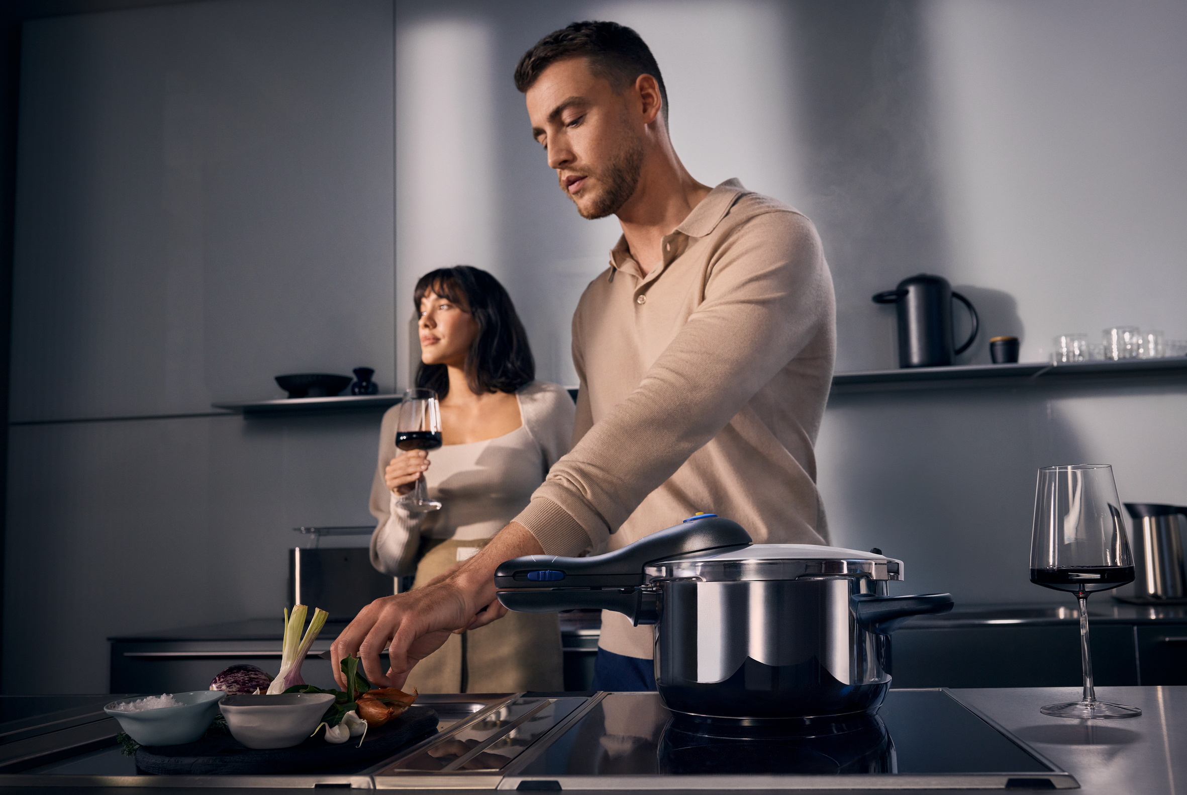 Ein Mann und eine Frau kochen in einer Küche. Ein Schnellkochtopf steht auf dem Herd.