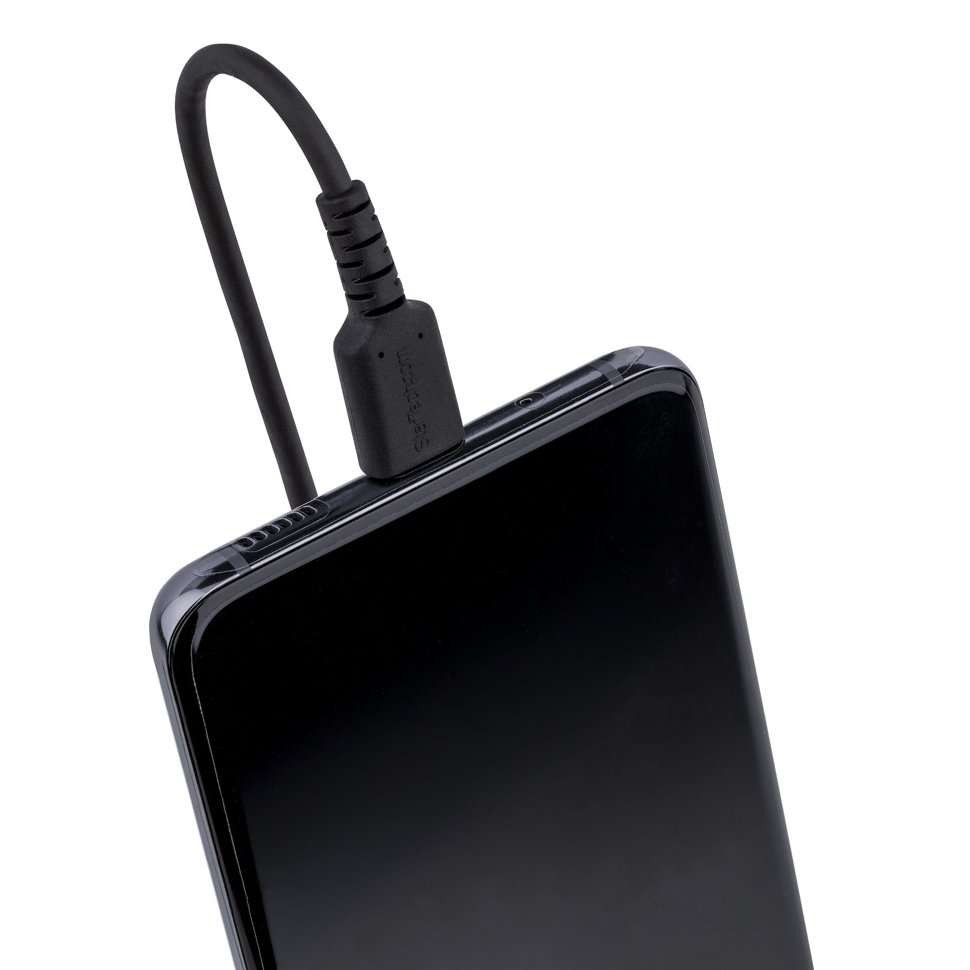 Un teléfono negro que se carga con un cable negro. El cable está enchufado al teléfono.