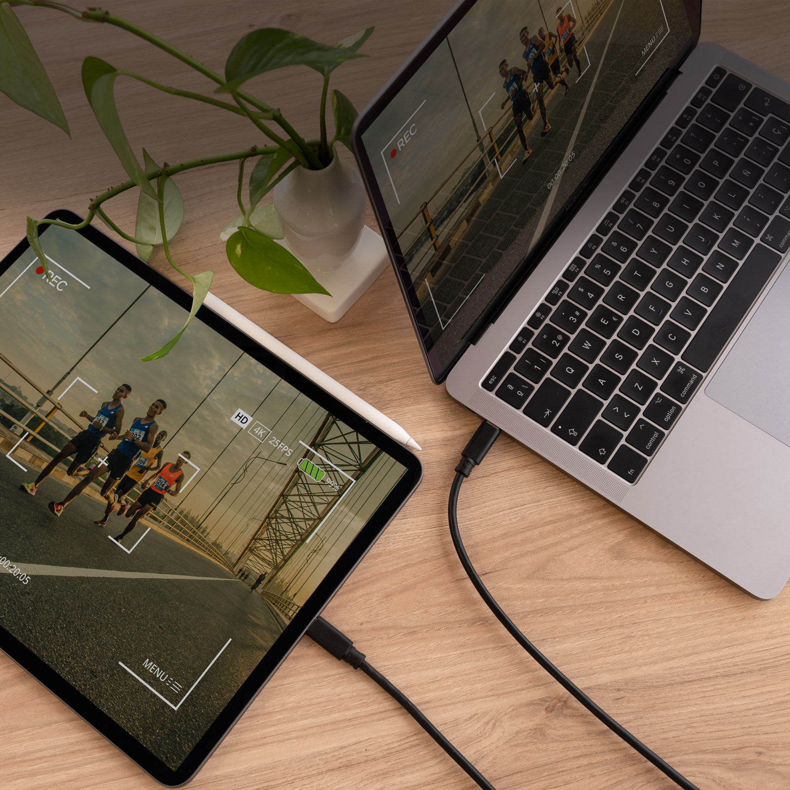 Laptop und Tablet auf Holztisch, beide zeigen ein Video. Schwarze Kabel.