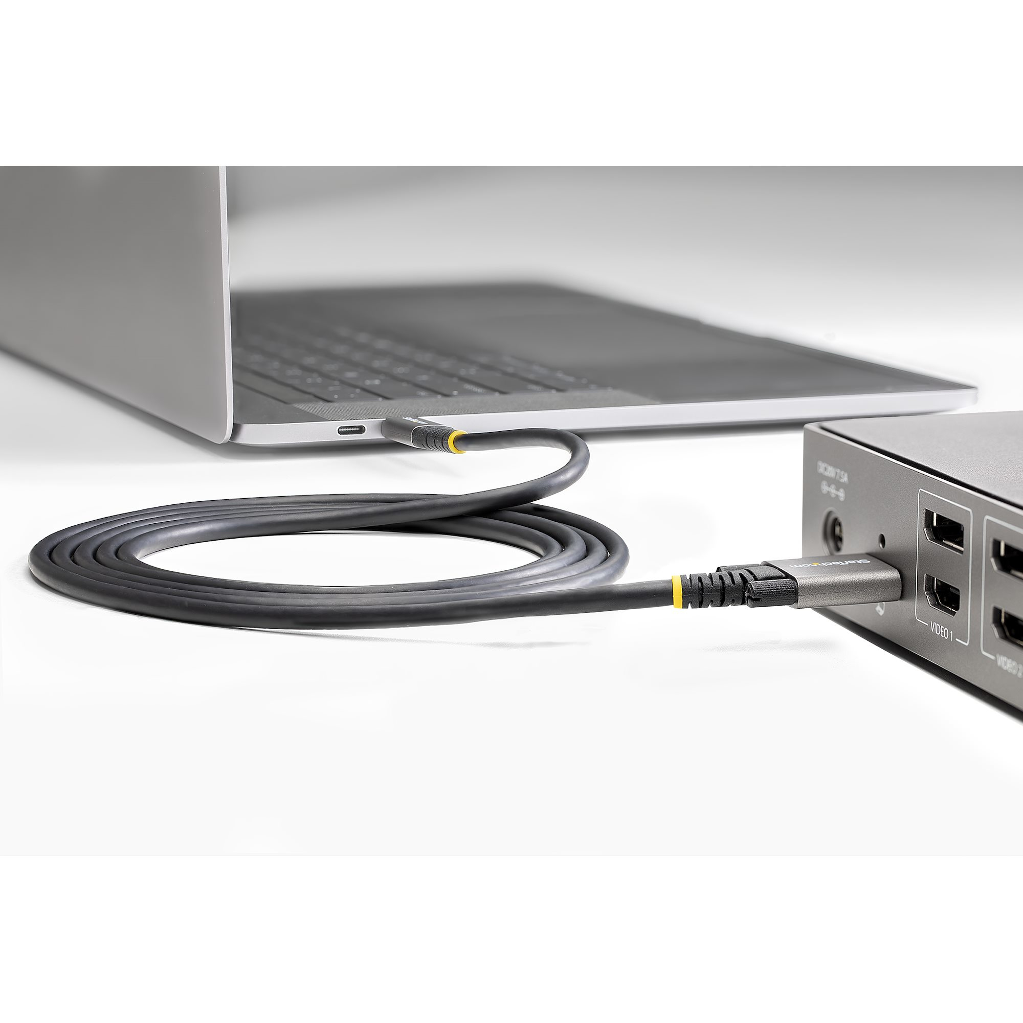 Ordenador portátil y un dispositivo conectado por cable. Cable gris con detalles amarillos.