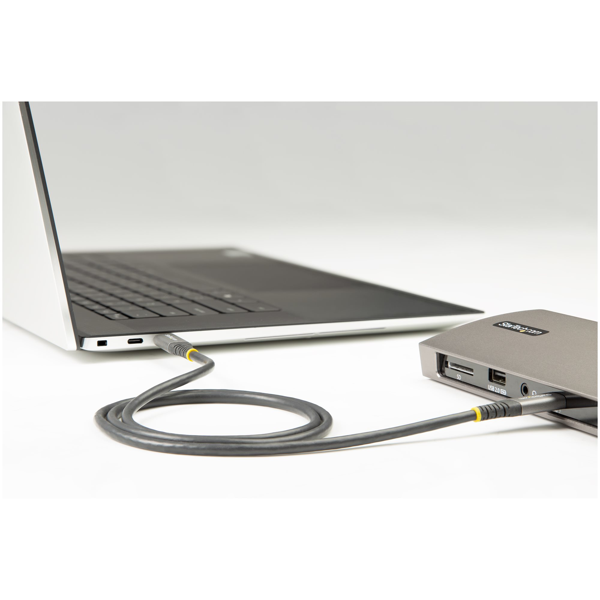 Portátil conectado a disco duro externo gris con cable.