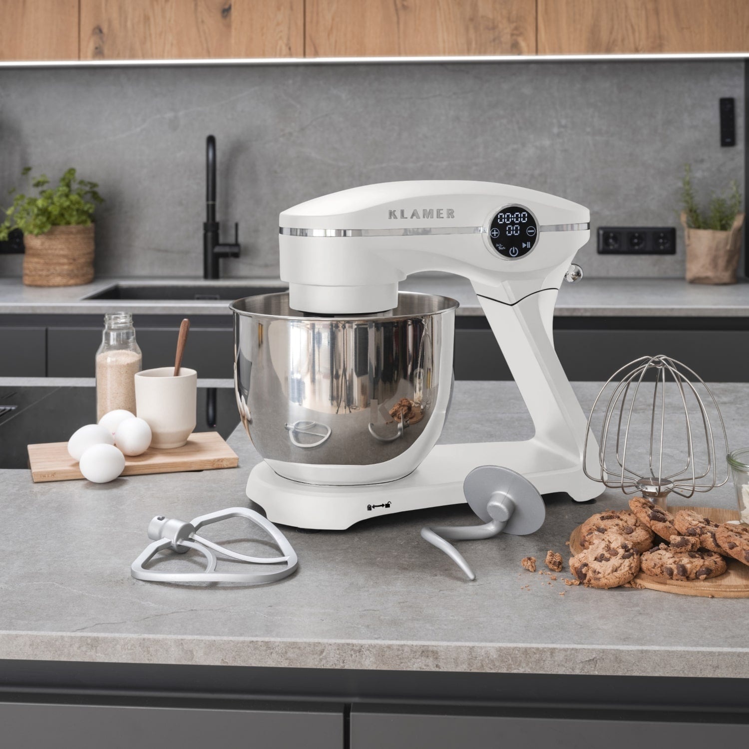 Weißer Küchenmixer mit Schüssel und Aufsätzen auf einer grauen Arbeitsplatte. Küche.