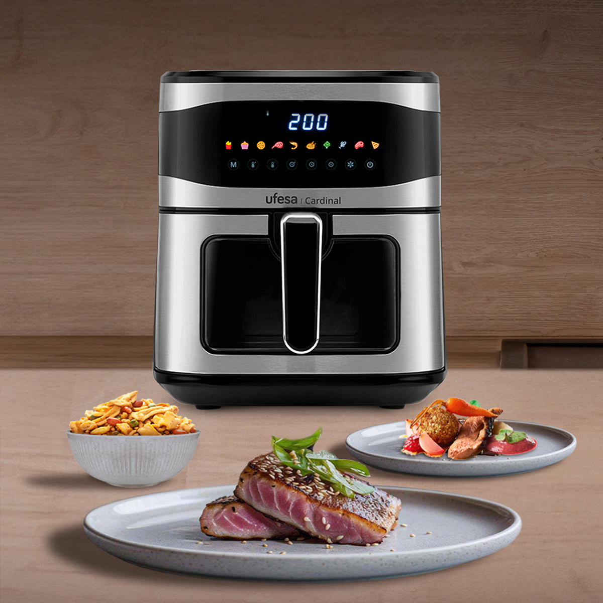 Frytownica powietrzna z talerzami z jedzeniem. Stal nierdzewna i czarny design. Drewniane tło.