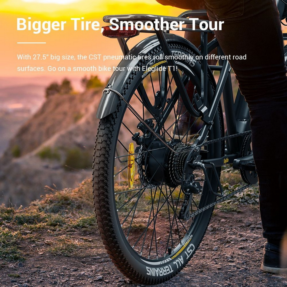 Osoba jadąca czarnym rowerem po polnej ścieżce z górą w tle. Na obrazie znajduje się tekst.