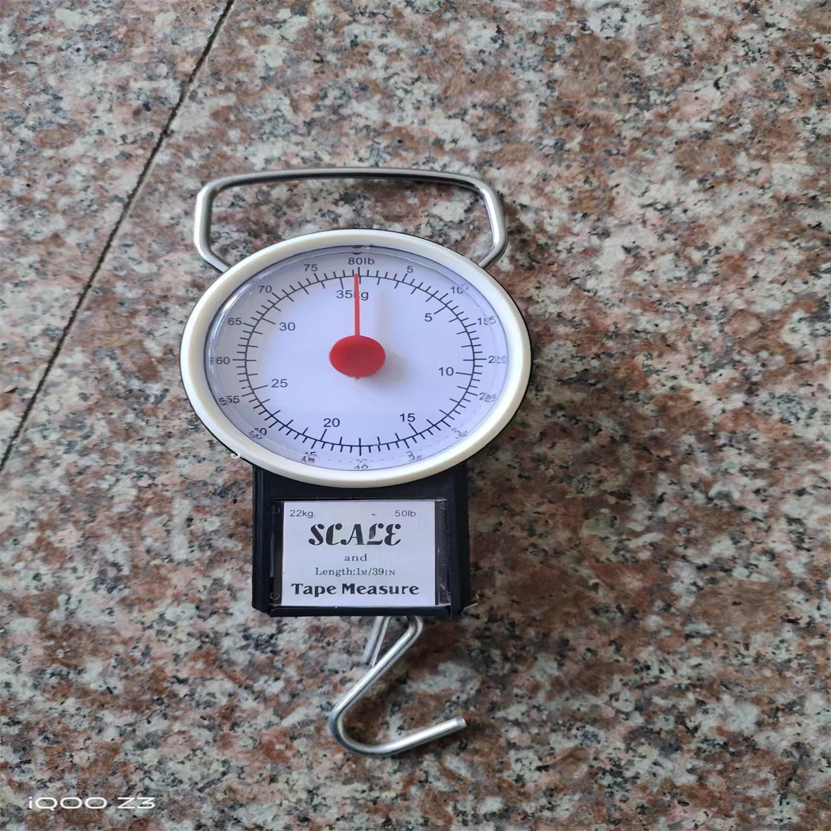 Ein Nachttisch mit digitalem Thermometer. Der Tisch hat Bücher und Dekoration. Weißes Bett.