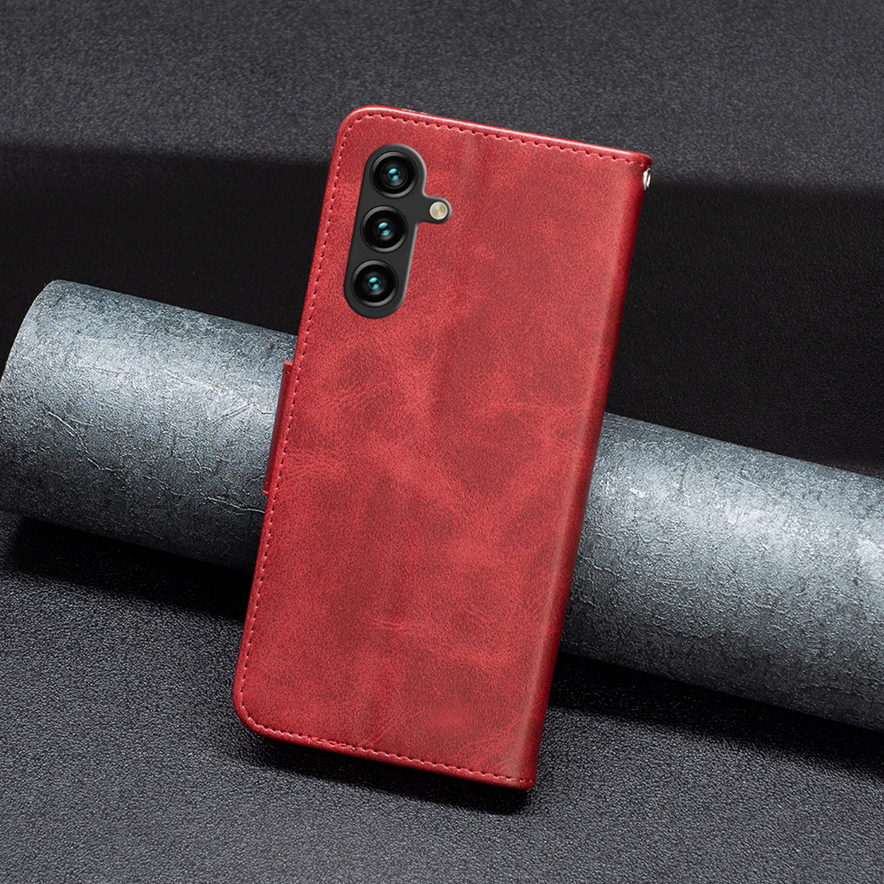 Étui de téléphone en cuir rouge sur une surface sombre. Il comporte des découpes pour l'appareil photo et un rabat.