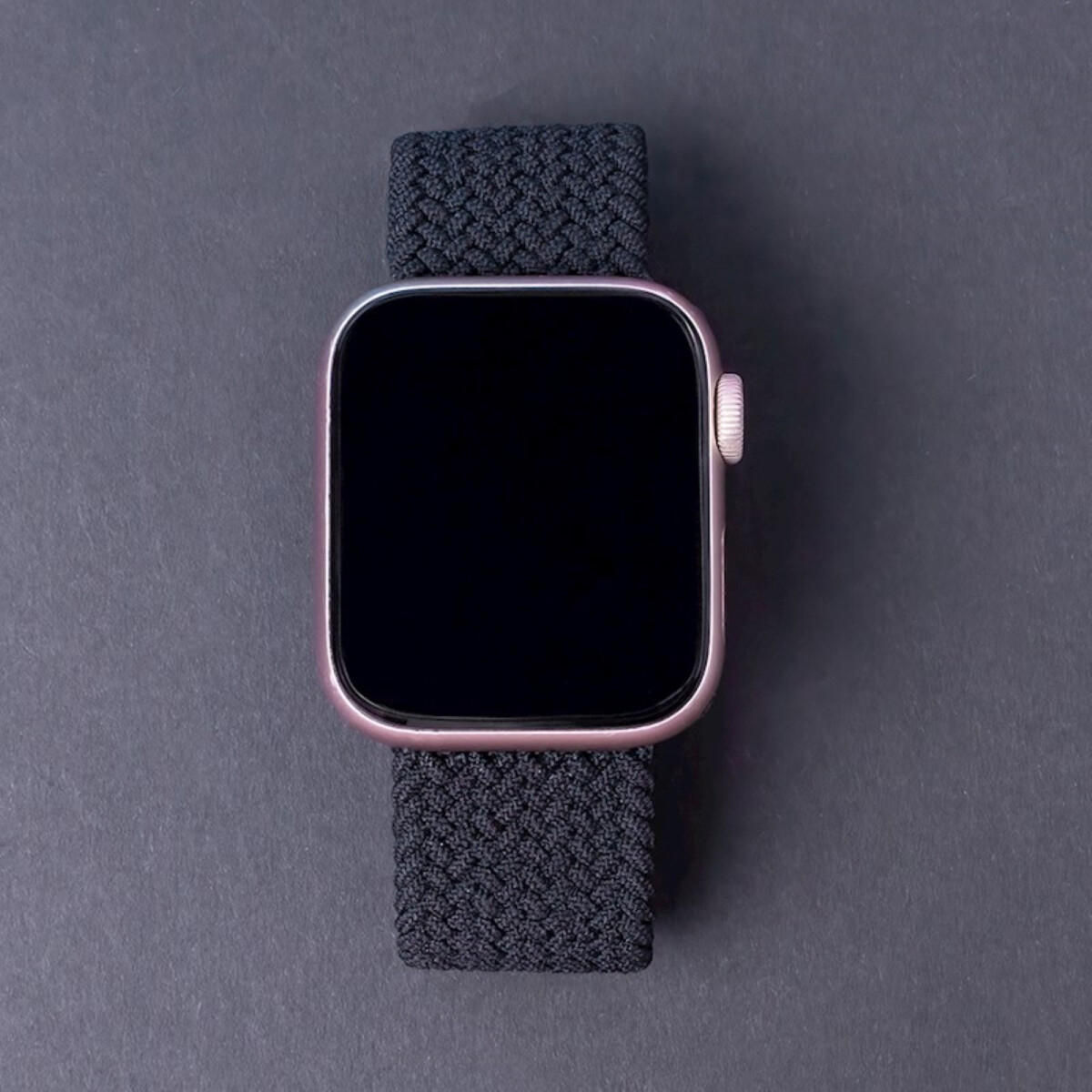 Apple Watch mit schwarzem Armband und rosafarbenem Gehäuse, Draufsicht.