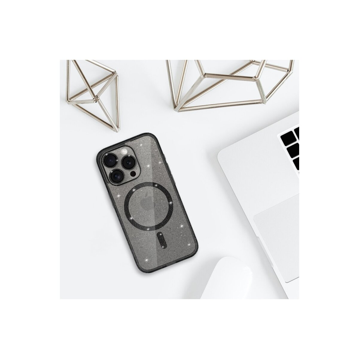 Custodia per telefono su superficie bianca, laptop e forme geometriche metalliche dietro.