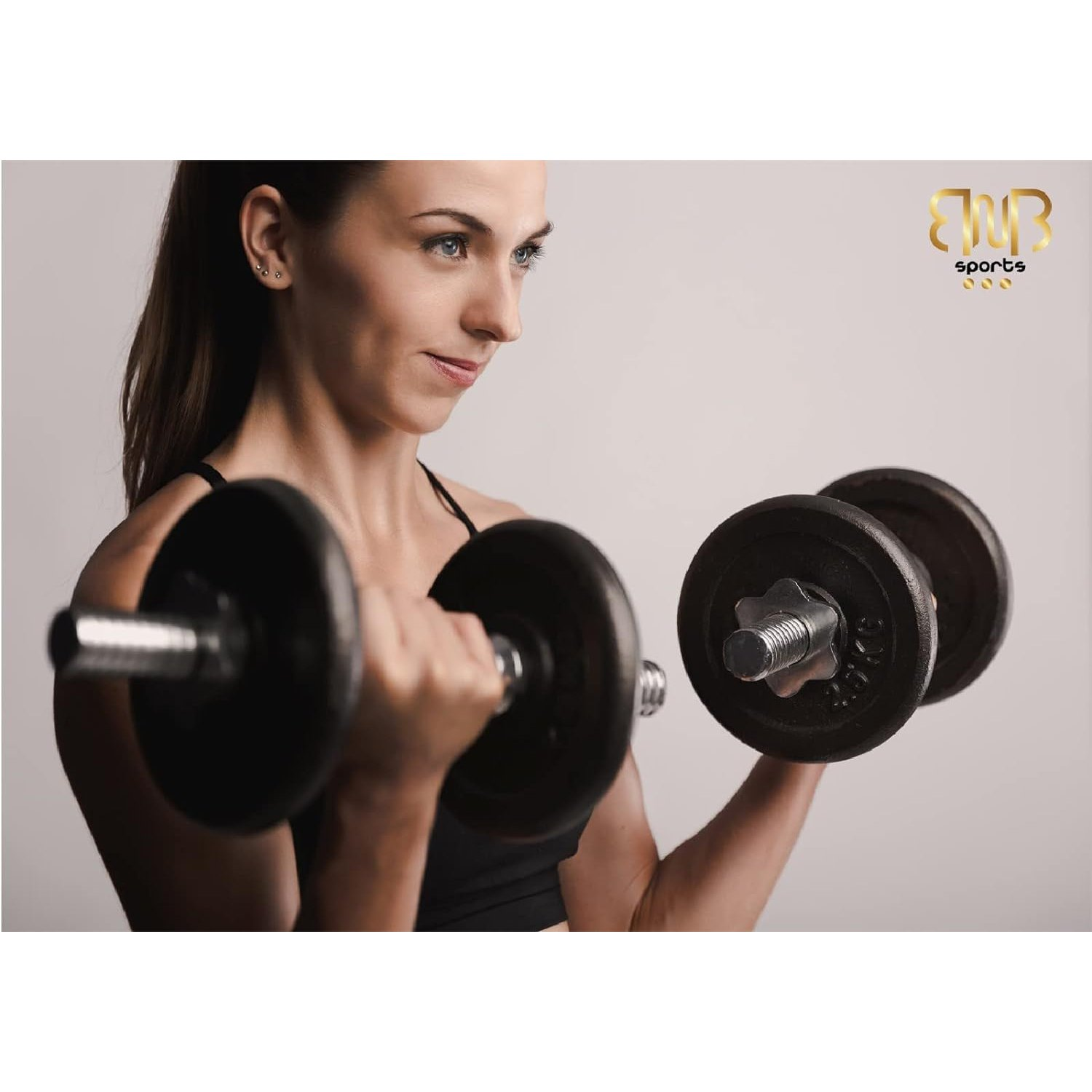 Frau in schwarzem Top trainiert mit schwarzen Hanteln. Weißer Hintergrund. BWB Sports Logo oben rechts.