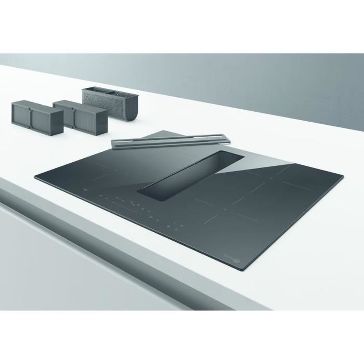 Czarna płyta indukcyjna ze zintegrowanym wentylatorem na białym blacie. Są trzy małe szafki.