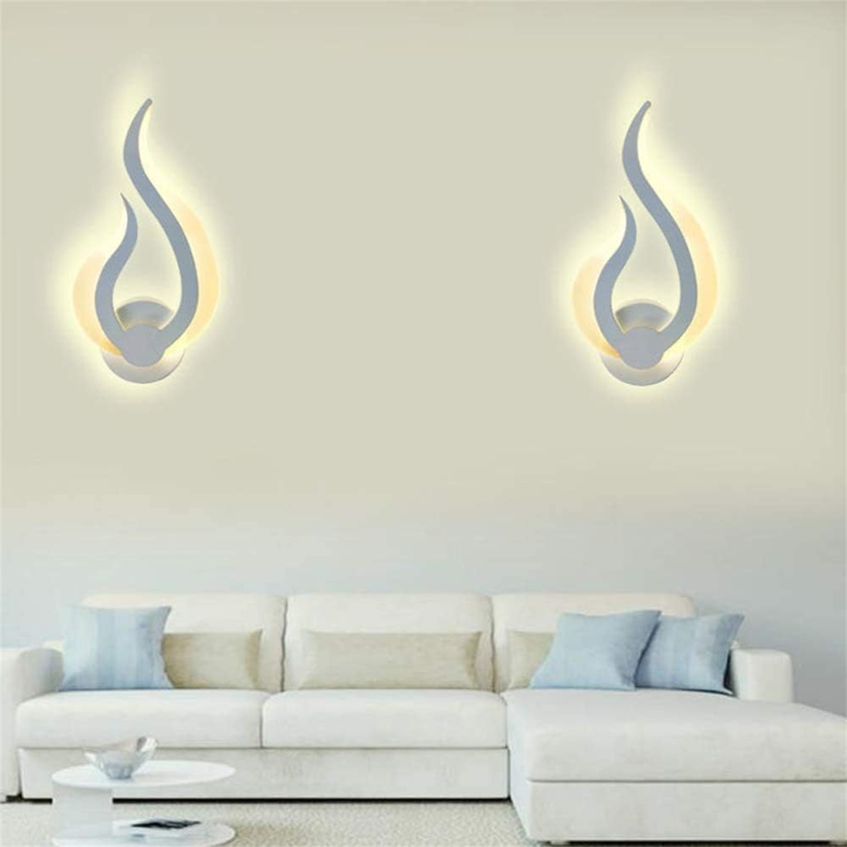 Zwei Wandleuchten mit einzigartigem flammenartigen Design über einem weißen Sofa.
